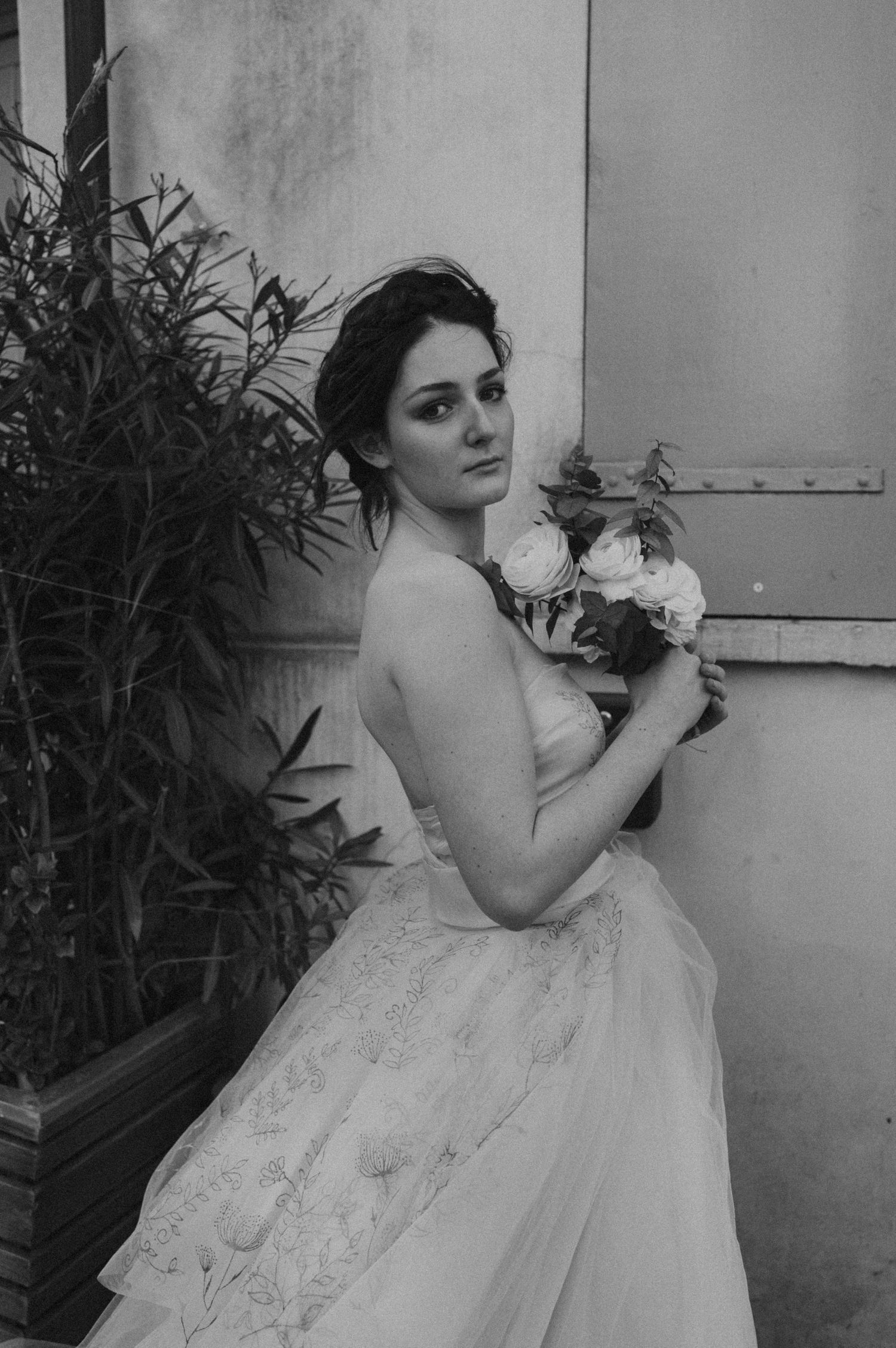 An elegant bridal portrait in black and white featuring a strapless gown and floral bouquet.