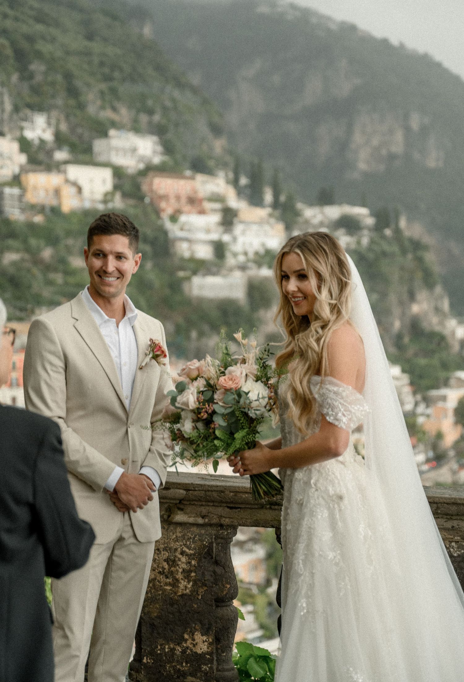 Wedding couple posing on a terrace overlooking the colorful coastal town of Positano, Italy.