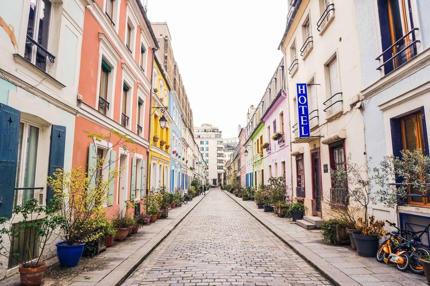 Charming cobblestone street in Paris lined with colorful buildings and potted plants.