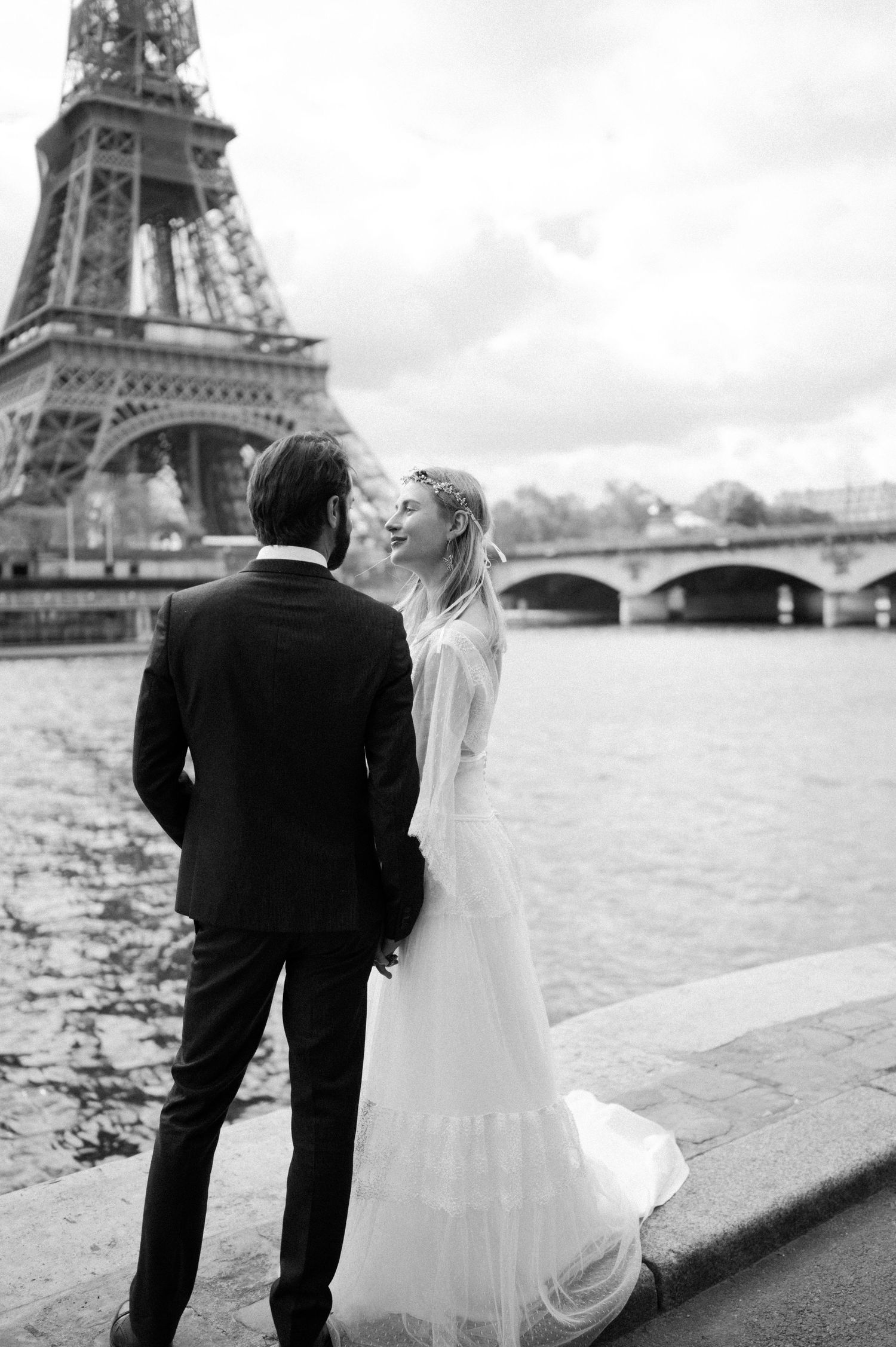 A tender moment between newlyweds along the Seine with Eiffel Tower in background.