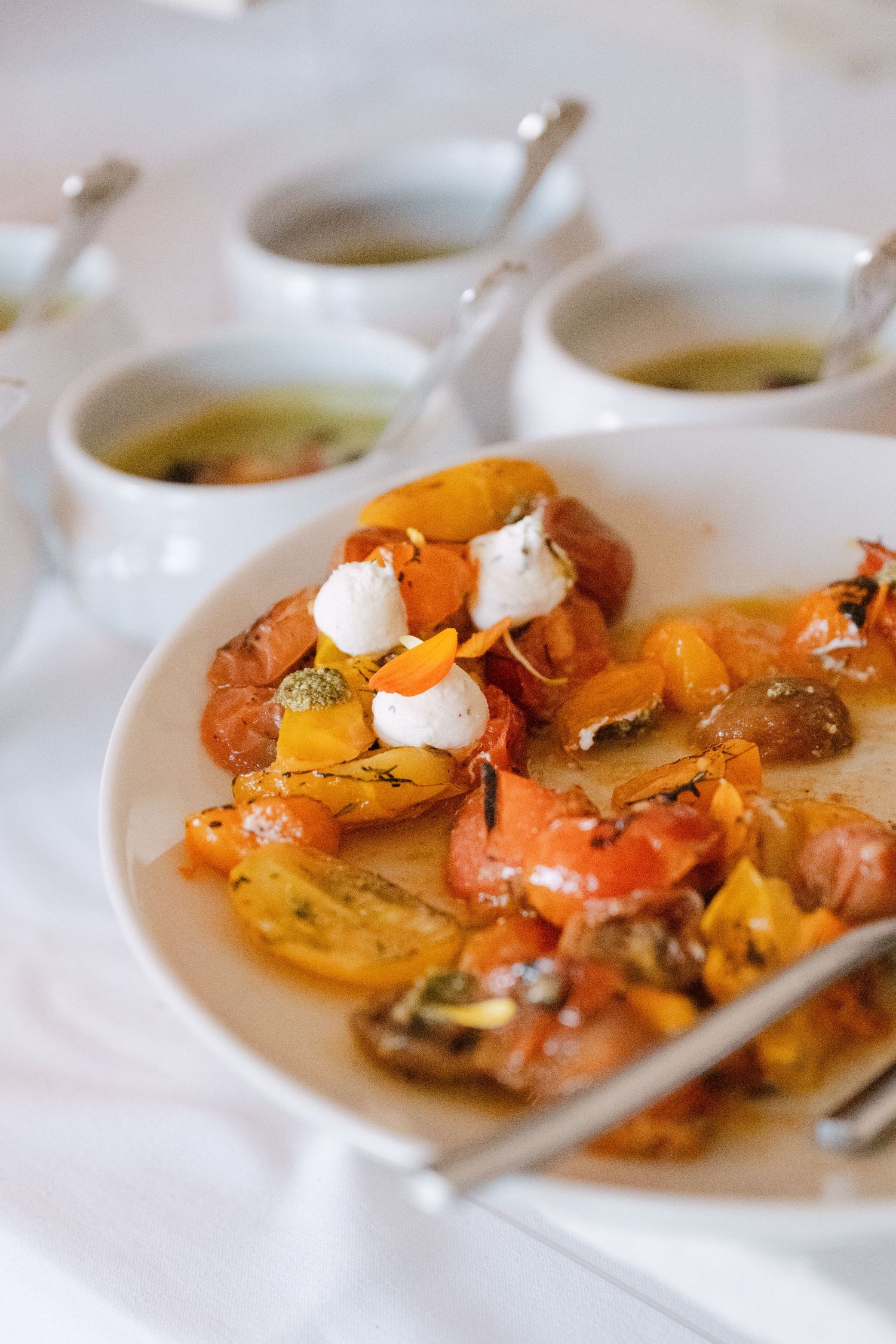 Colorful heirloom tomato salad with cream garnish on a white plate at a wedding.