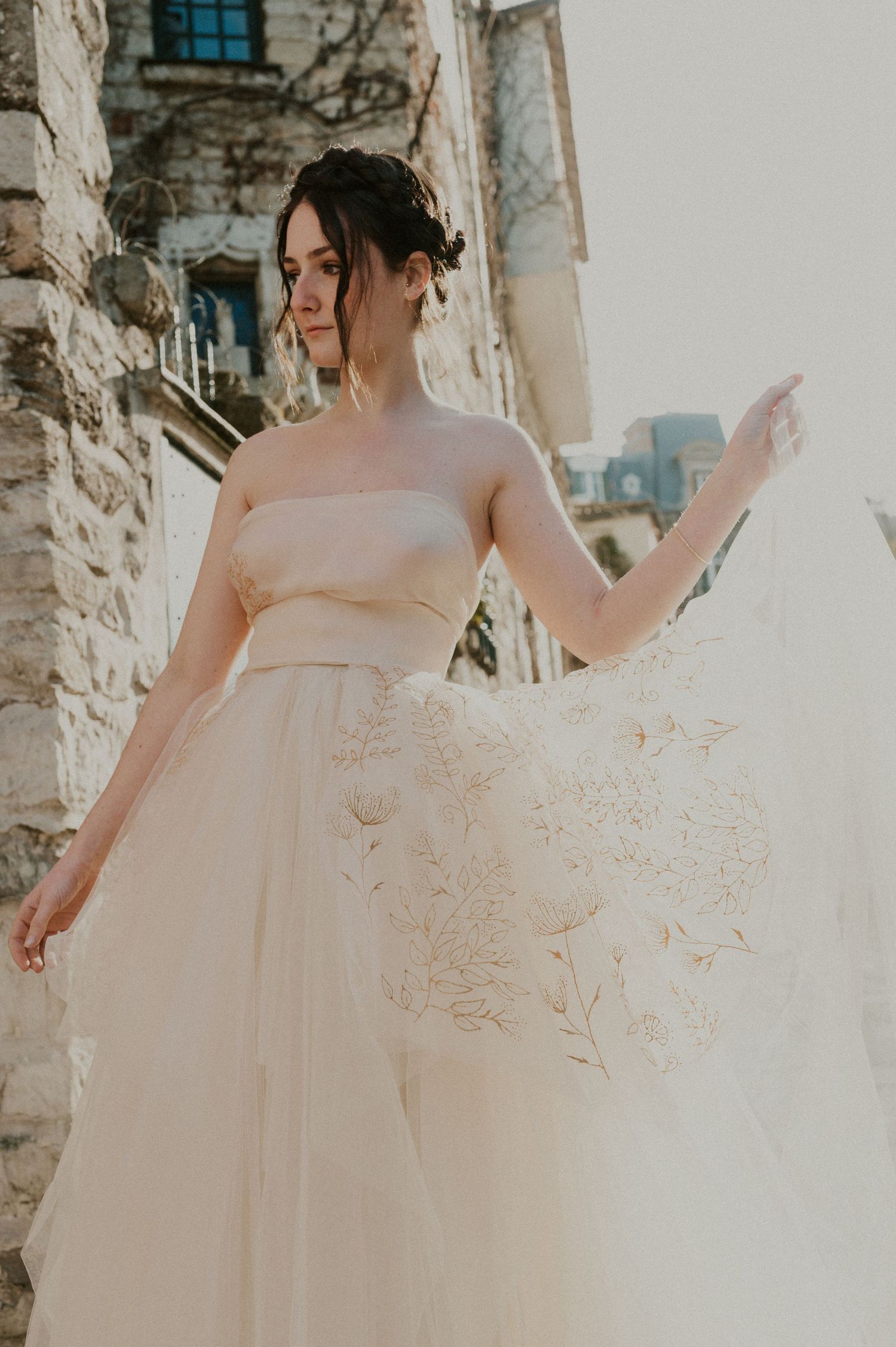 Ethereal bridal portrait showing flowing tulle gown details against stone architecture.