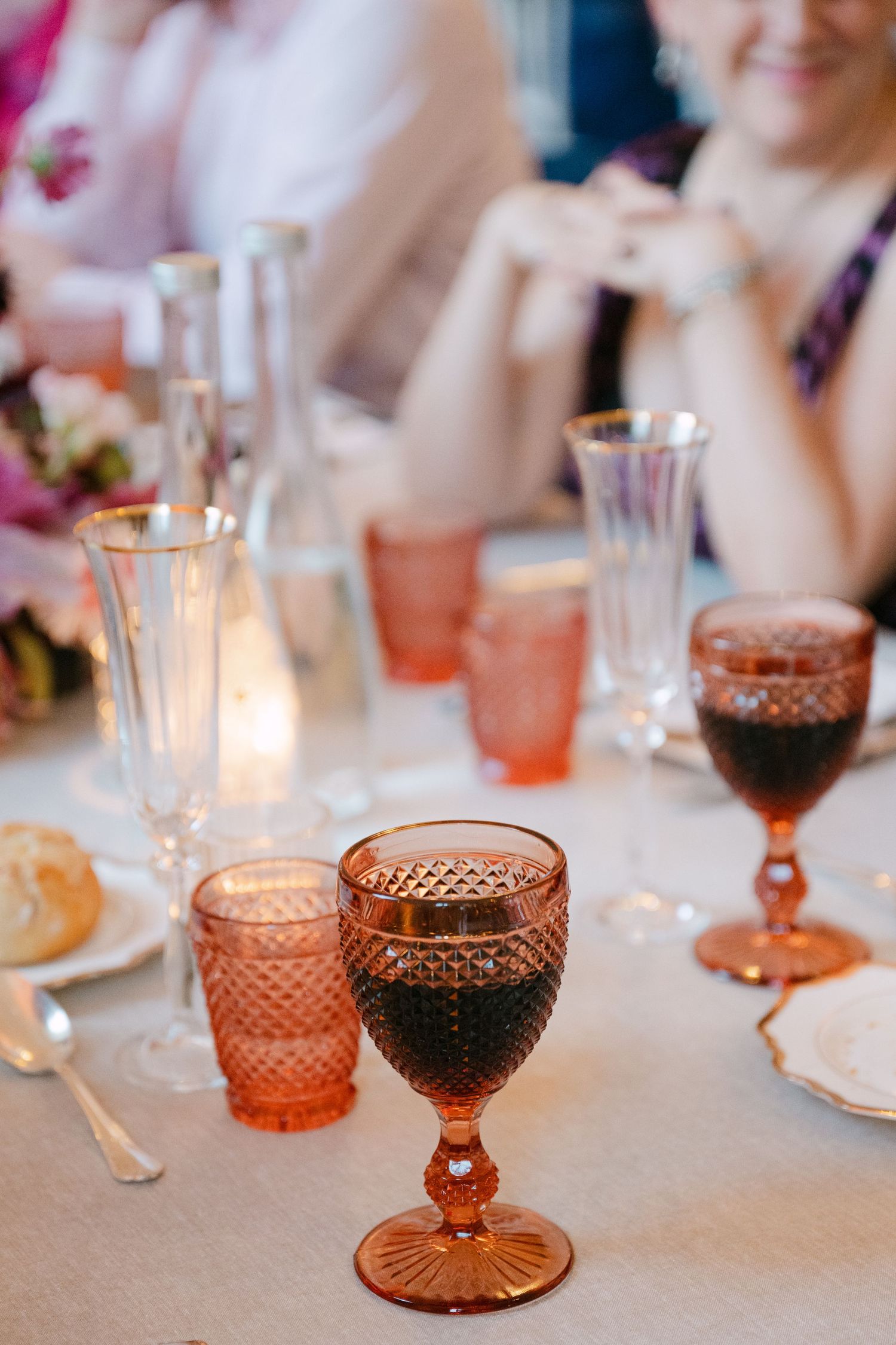 Elegant amber and pink vintage glassware on a candlelit wedding reception table.
