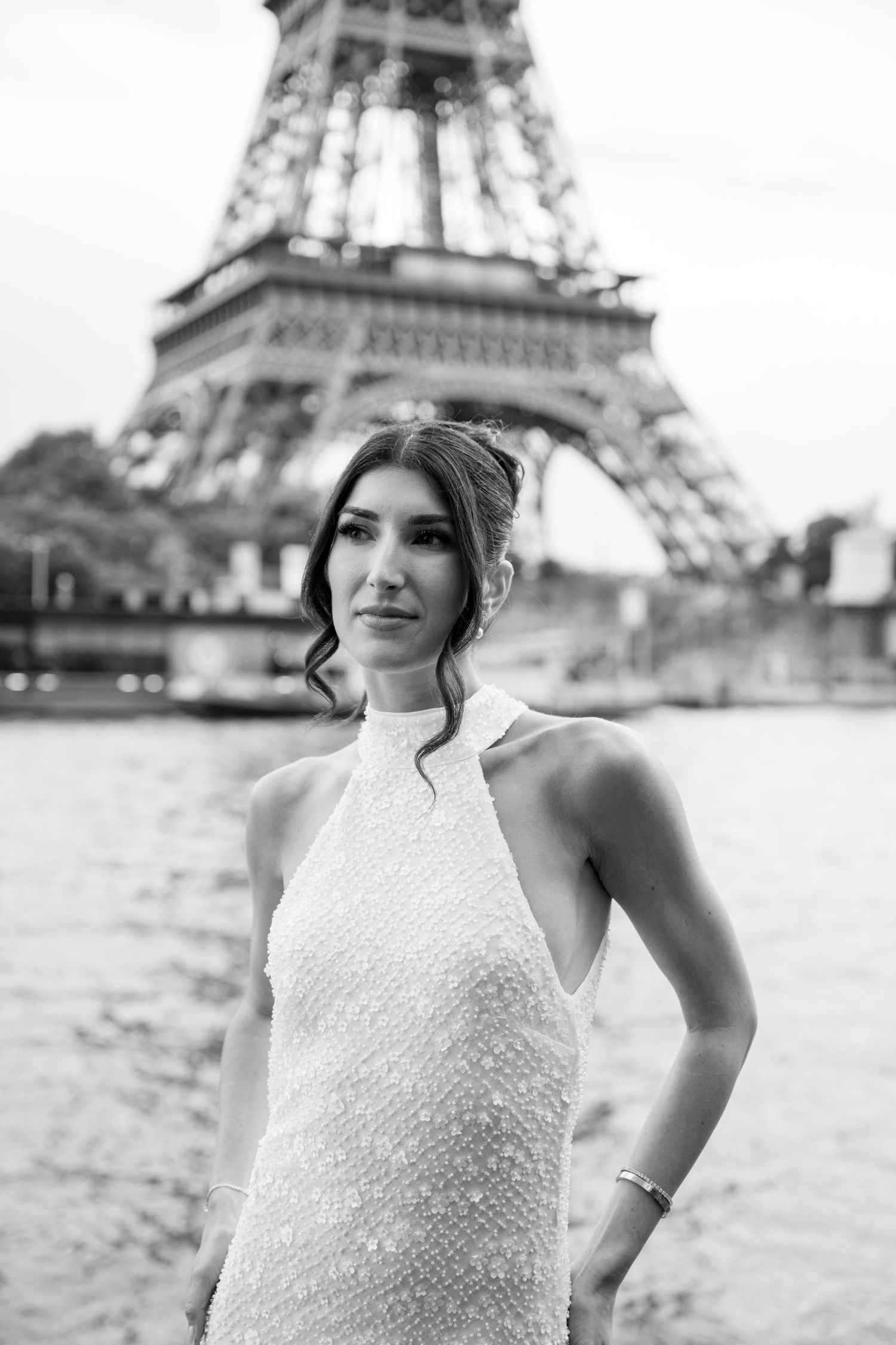 Black and white portrait of bride in halter neck gown posing in front of the Eiffel Tower in Paris.