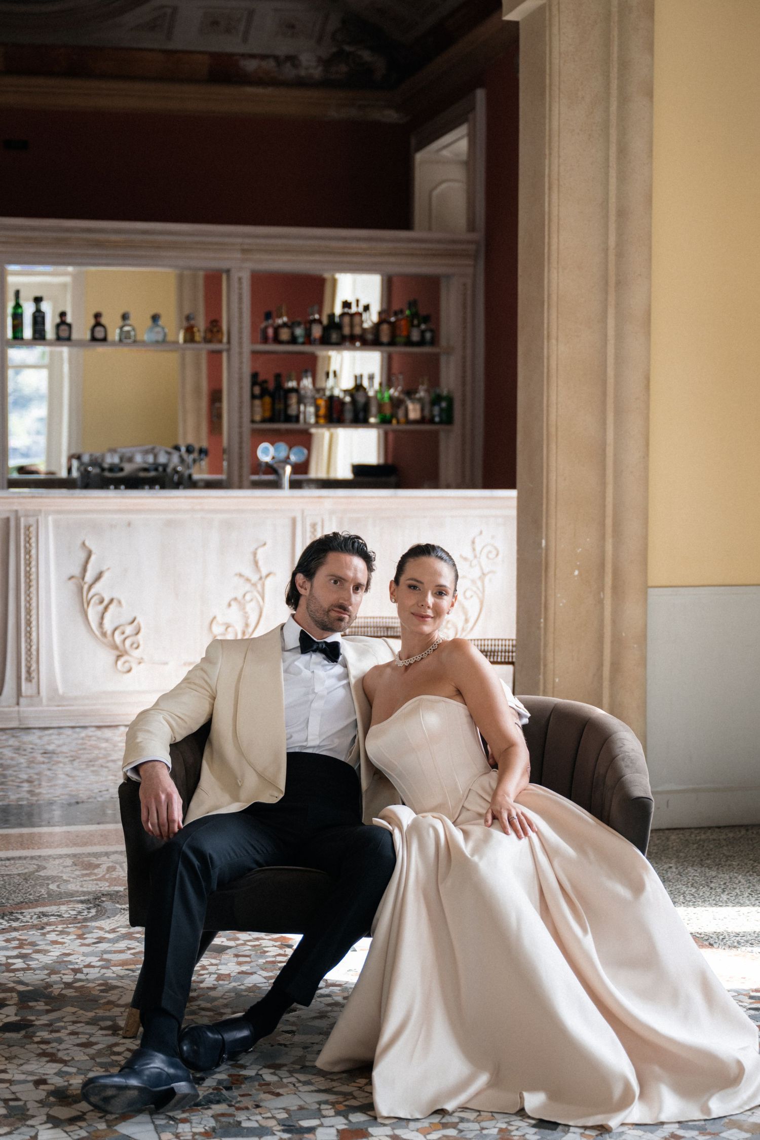 Sophisticated newlyweds posing in elegant hotel bar interior at Lake Como wedding venue.