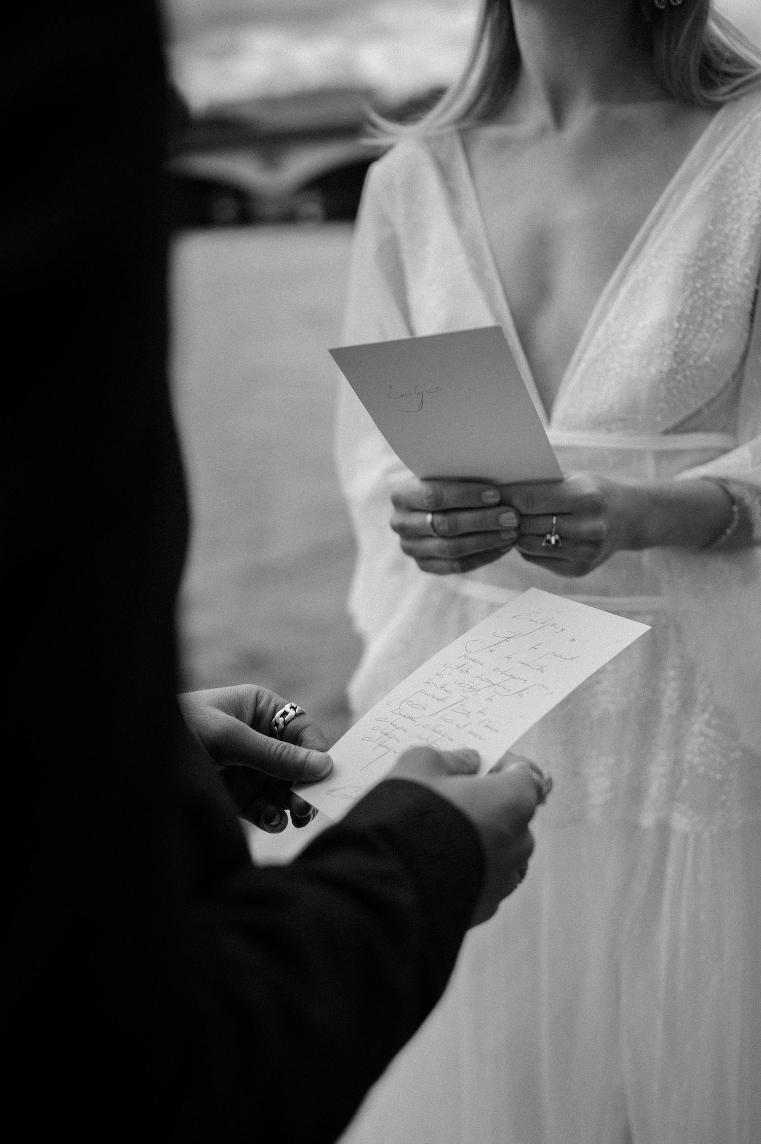 A couple exchanging handwritten vows during an intimate wedding ceremony, captured in black and white.