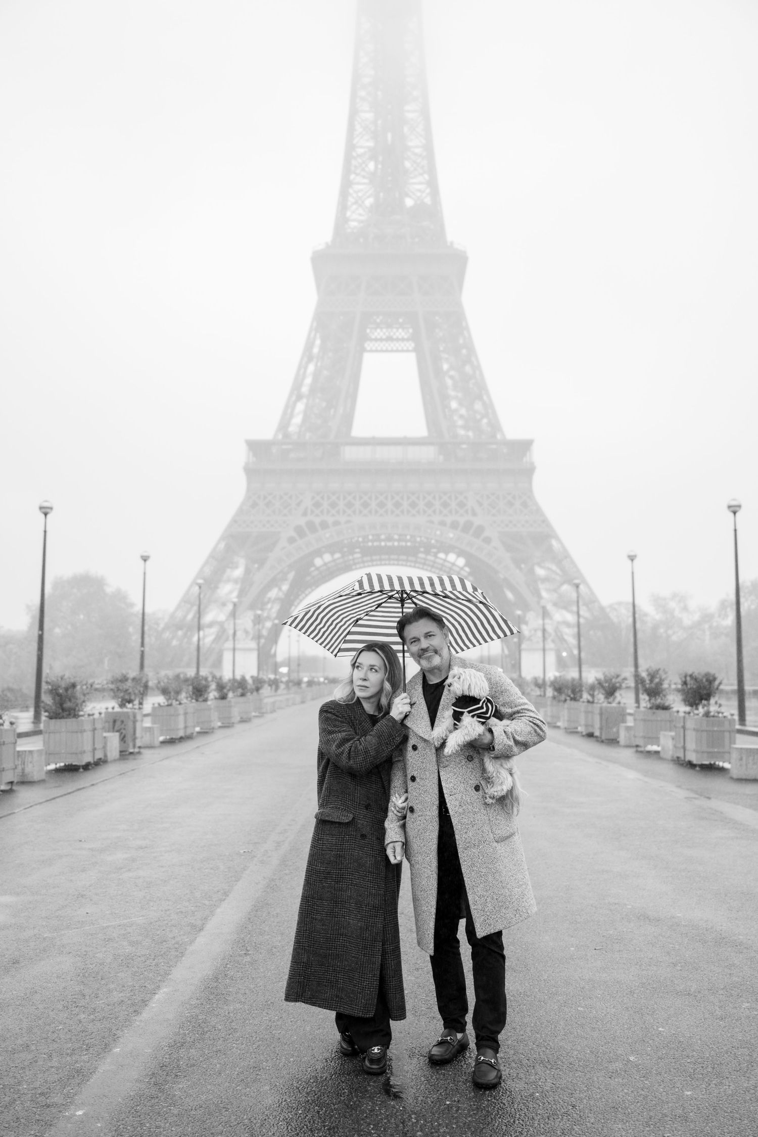 Romantic wedding photo of a couple embracing in front of the Eiffel Tower in black and white.