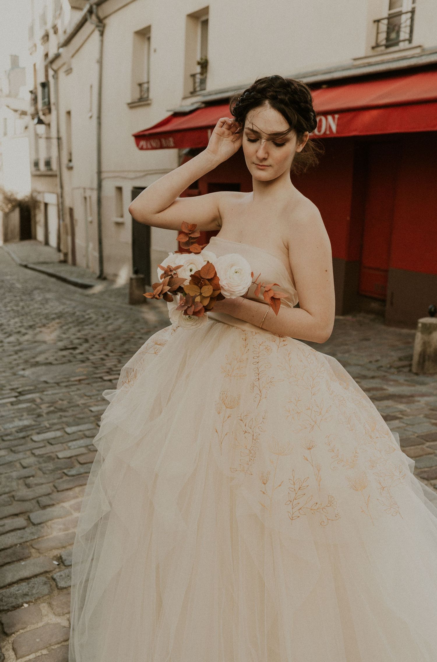 A dreamy bridal portrait on cobblestone streets with a red awning in the background.