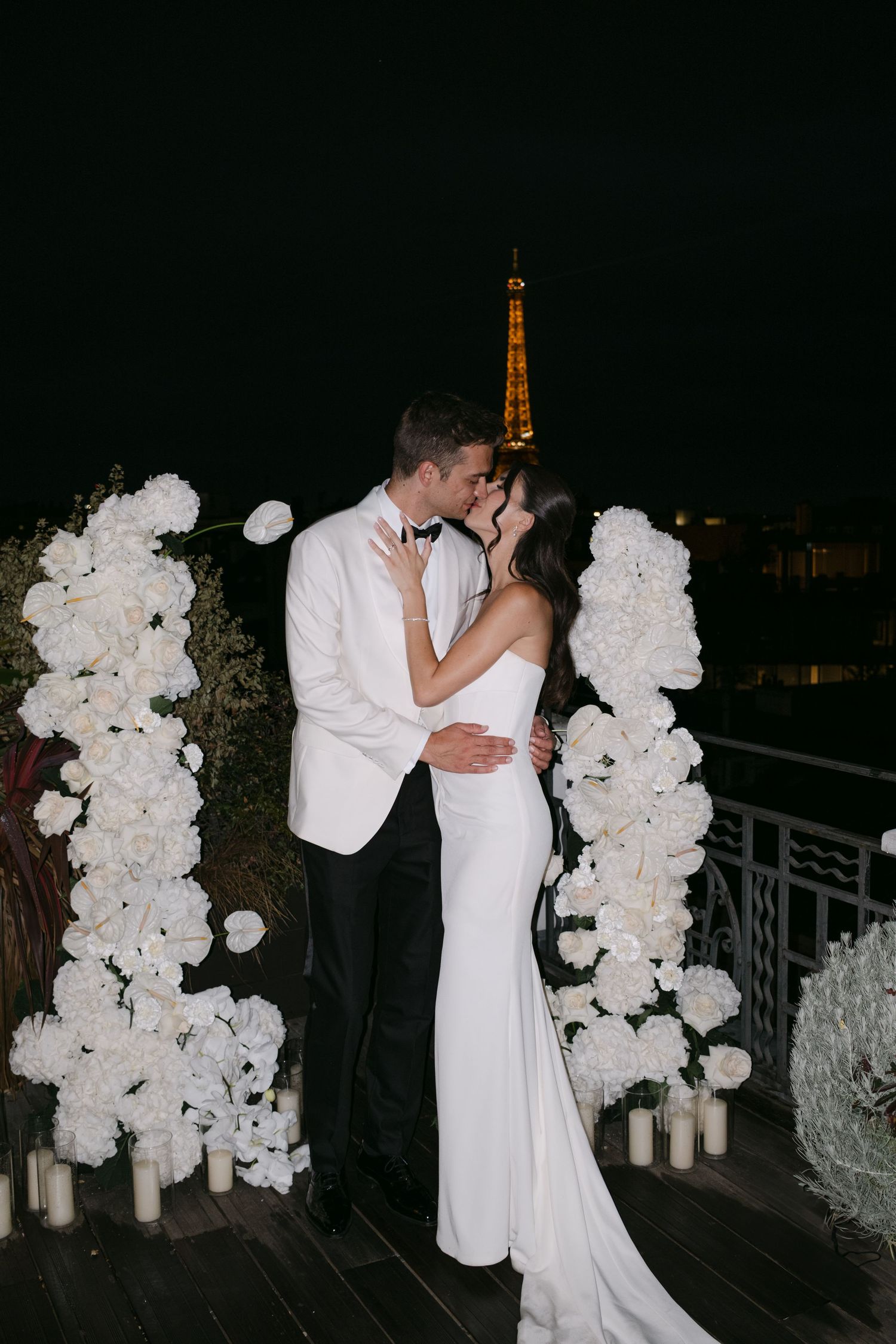 Newlyweds sharing romantic kiss with glowing Eiffel Tower backdrop at Paris wedding.