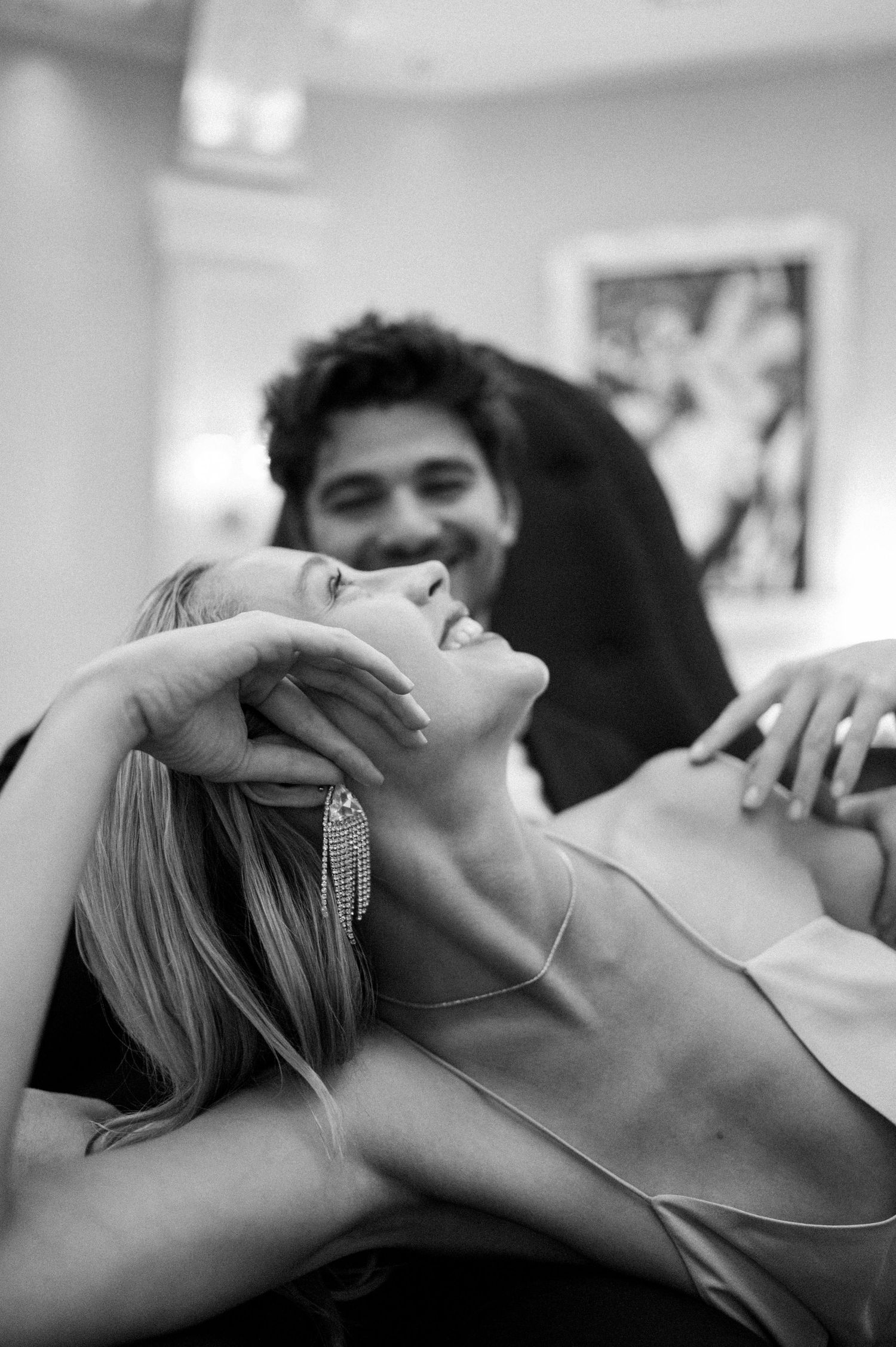 Black and white photo of a woman laughing joyfully while a man smiles warmly behind her.