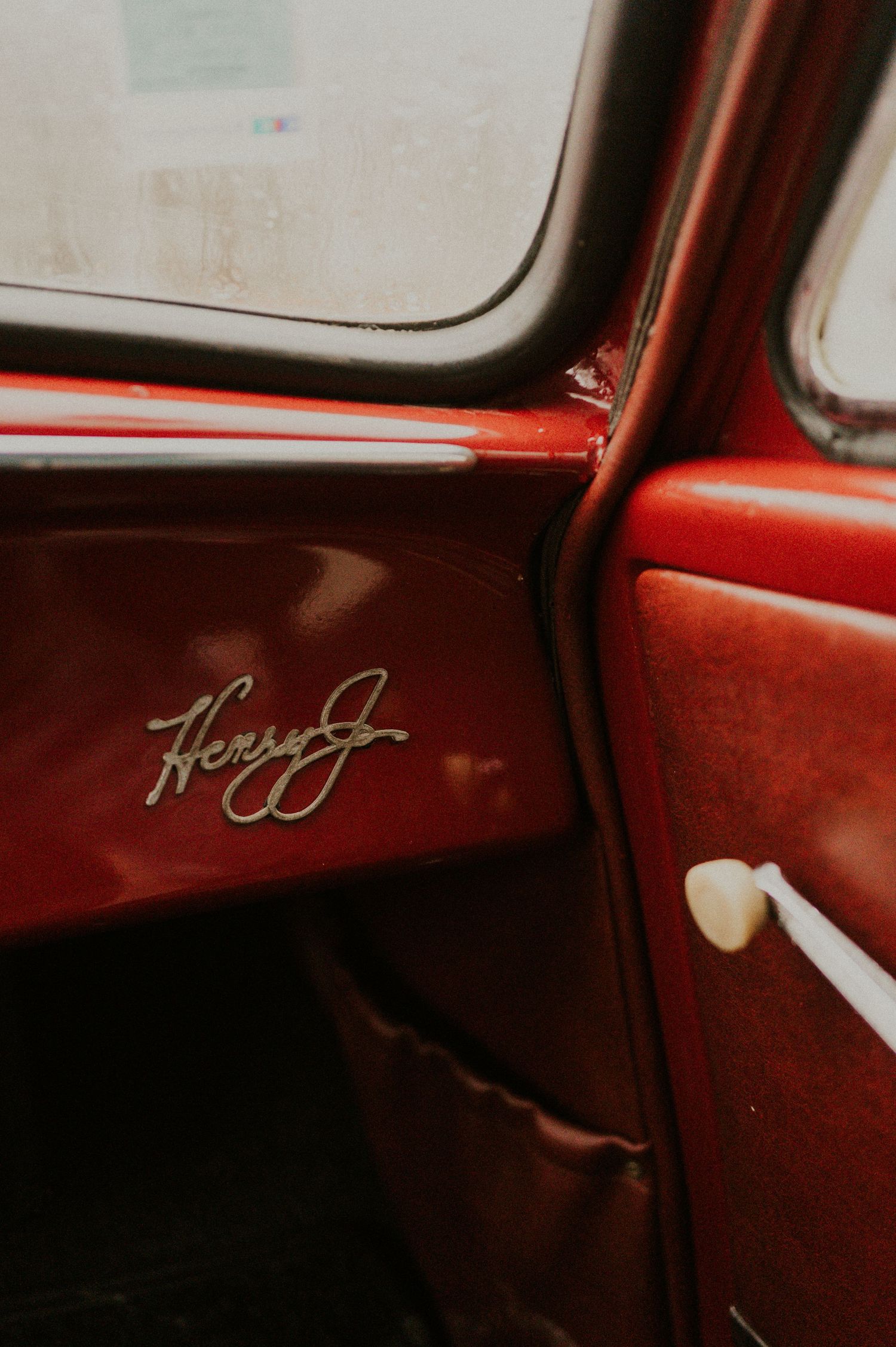 Close-up detail of vintage red car interior showing classic script signature branding.