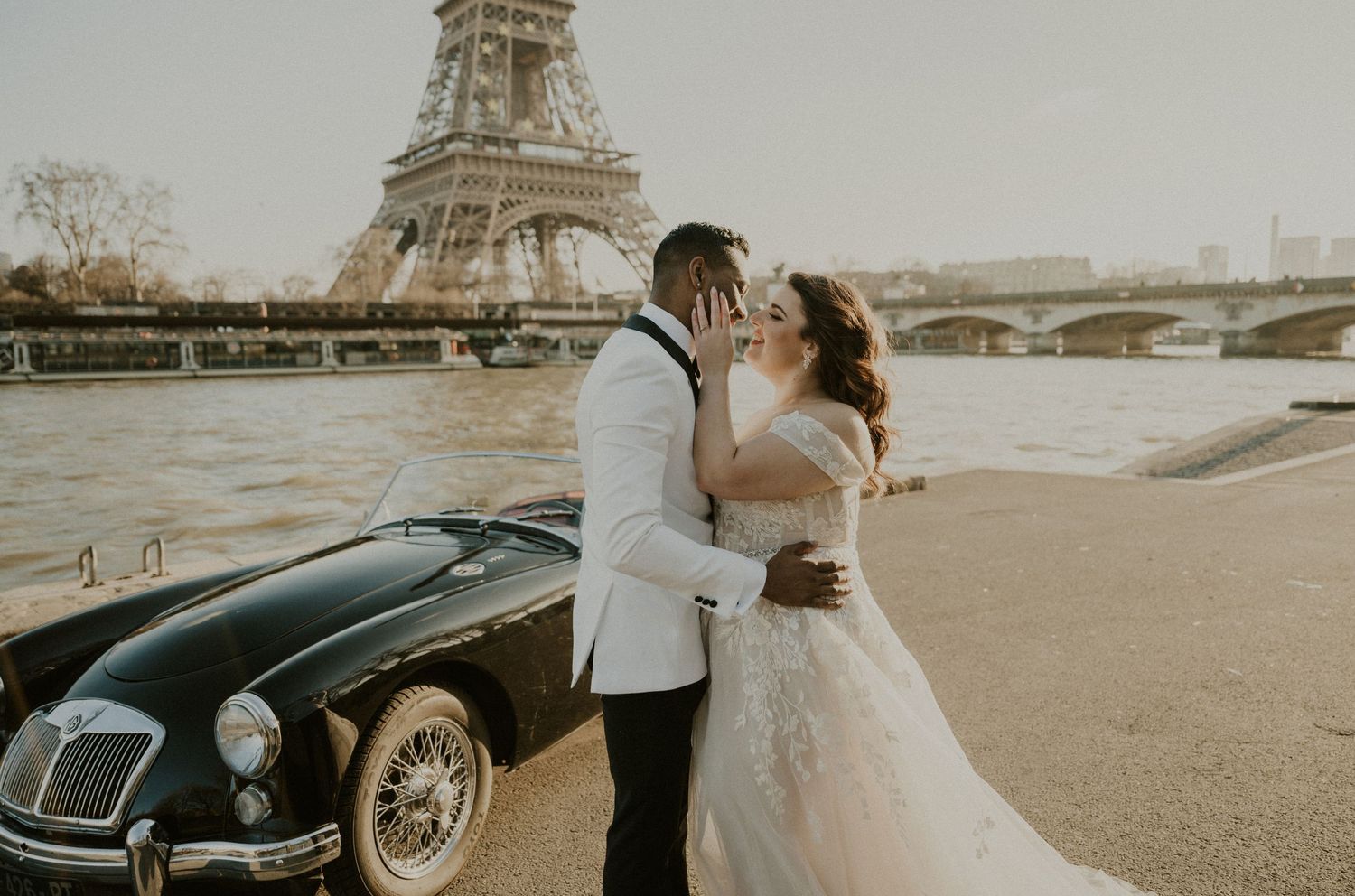 Wedding couple by classic car with Eiffel Tower view in golden hour light.