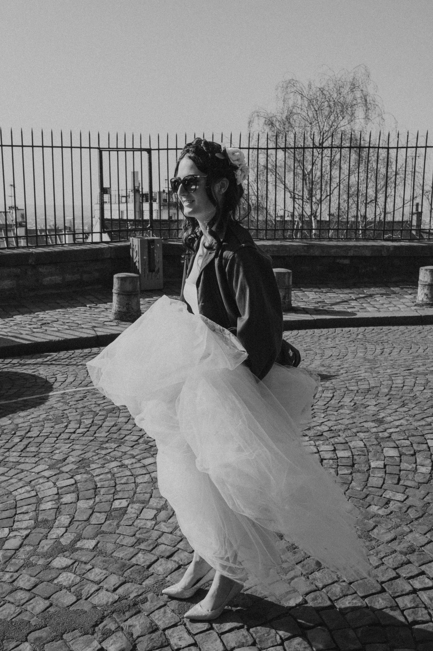 Black and white photo showing contrast between tough leather jacket and delicate tulle skirt on cobblestones.