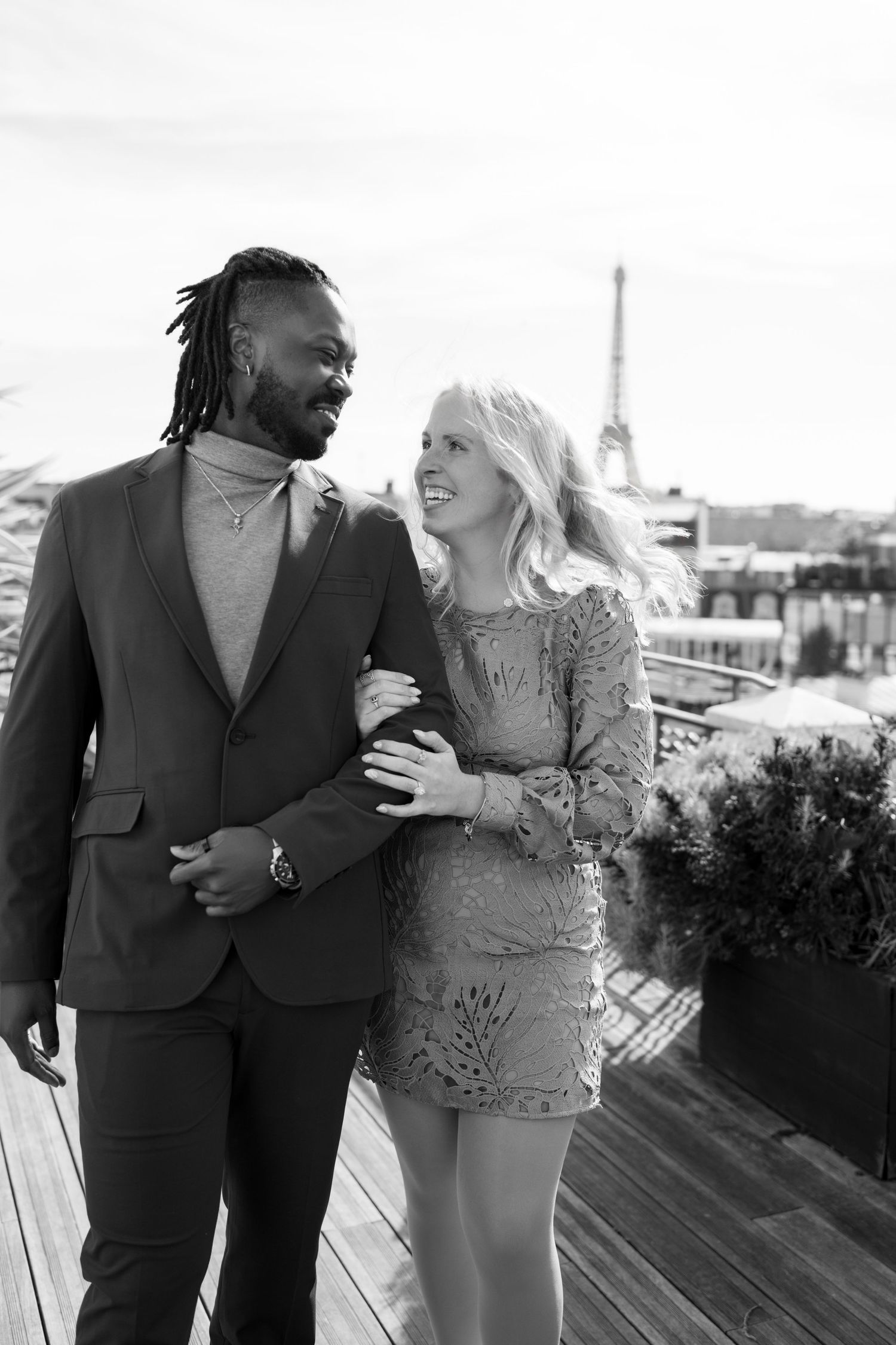 Couple embracing on a Paris rooftop terrace with the Eiffel Tower in the background, black and white photo.