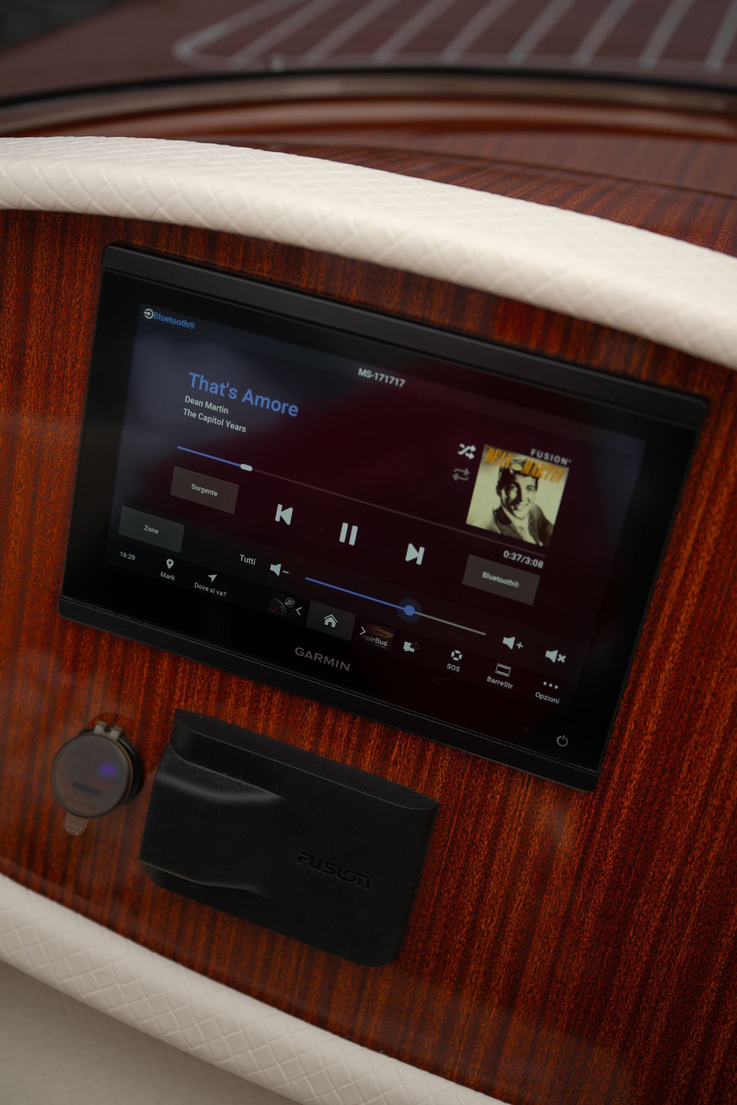 Garmin marine stereo display playing That's Amore on a luxury wooden boat dashboard.