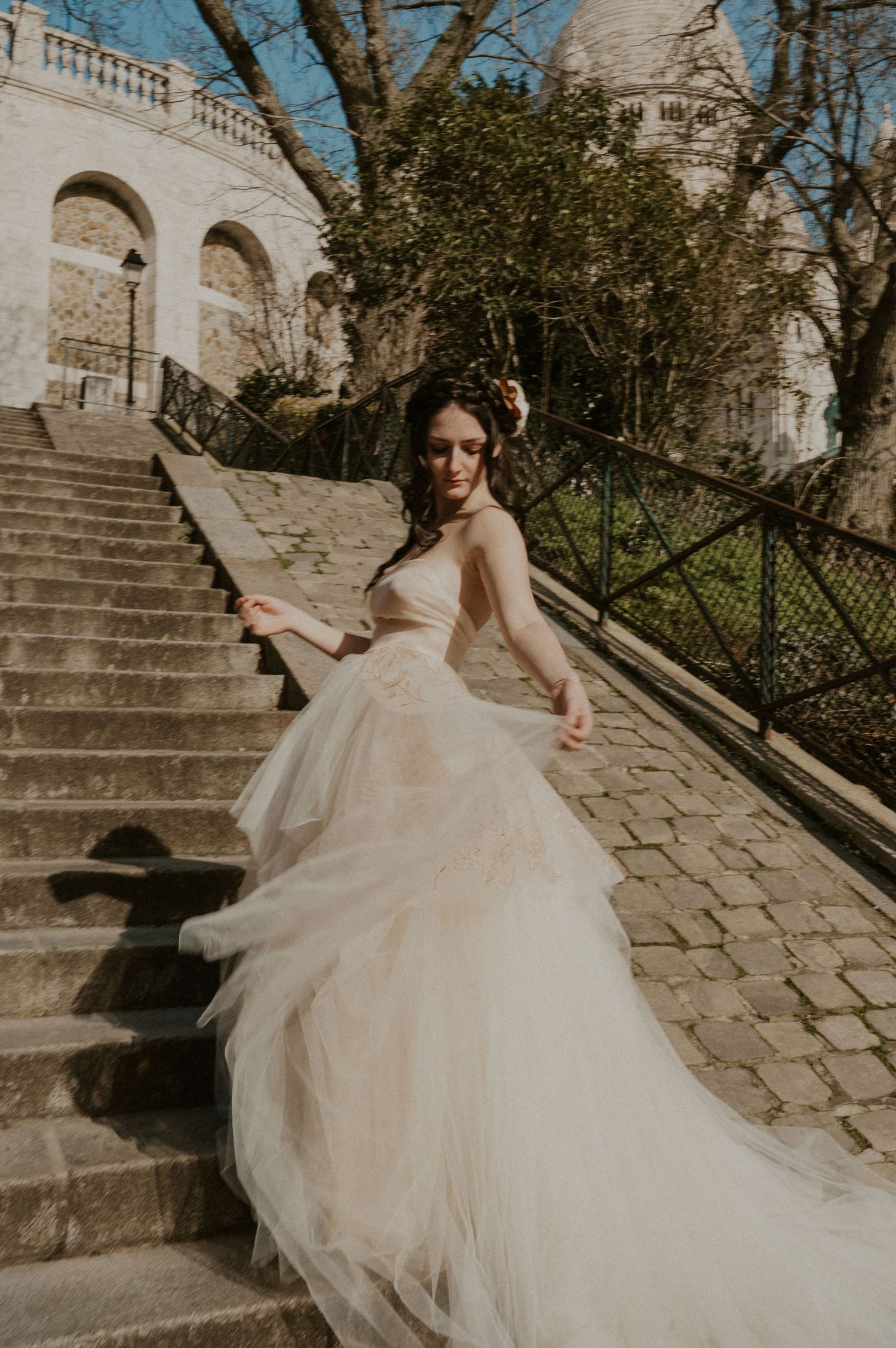 Romantic bridal portrait with flowing tulle gown against historic architecture and stone steps.