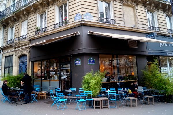 Corner cafe in Paris with bright blue outdoor furniture and classic Haussmanian architecture.