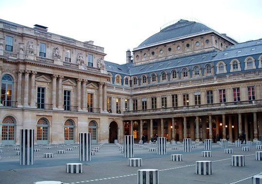 Symmetrical neoclassical building facade with geometric striped courtyard in Paris.
