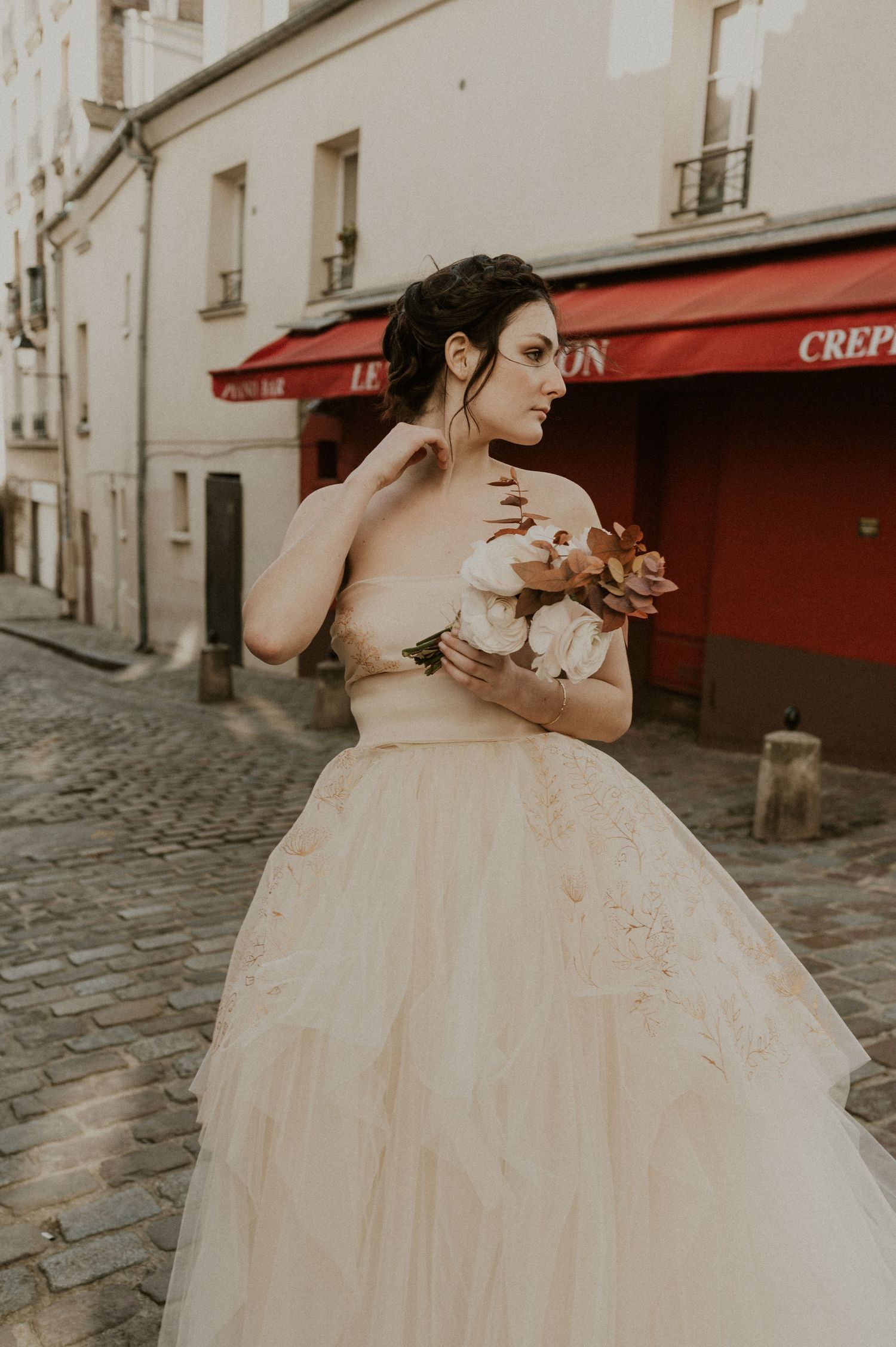A vintage-styled bridal portrait on Paris cobblestone streets with red storefront awnings.