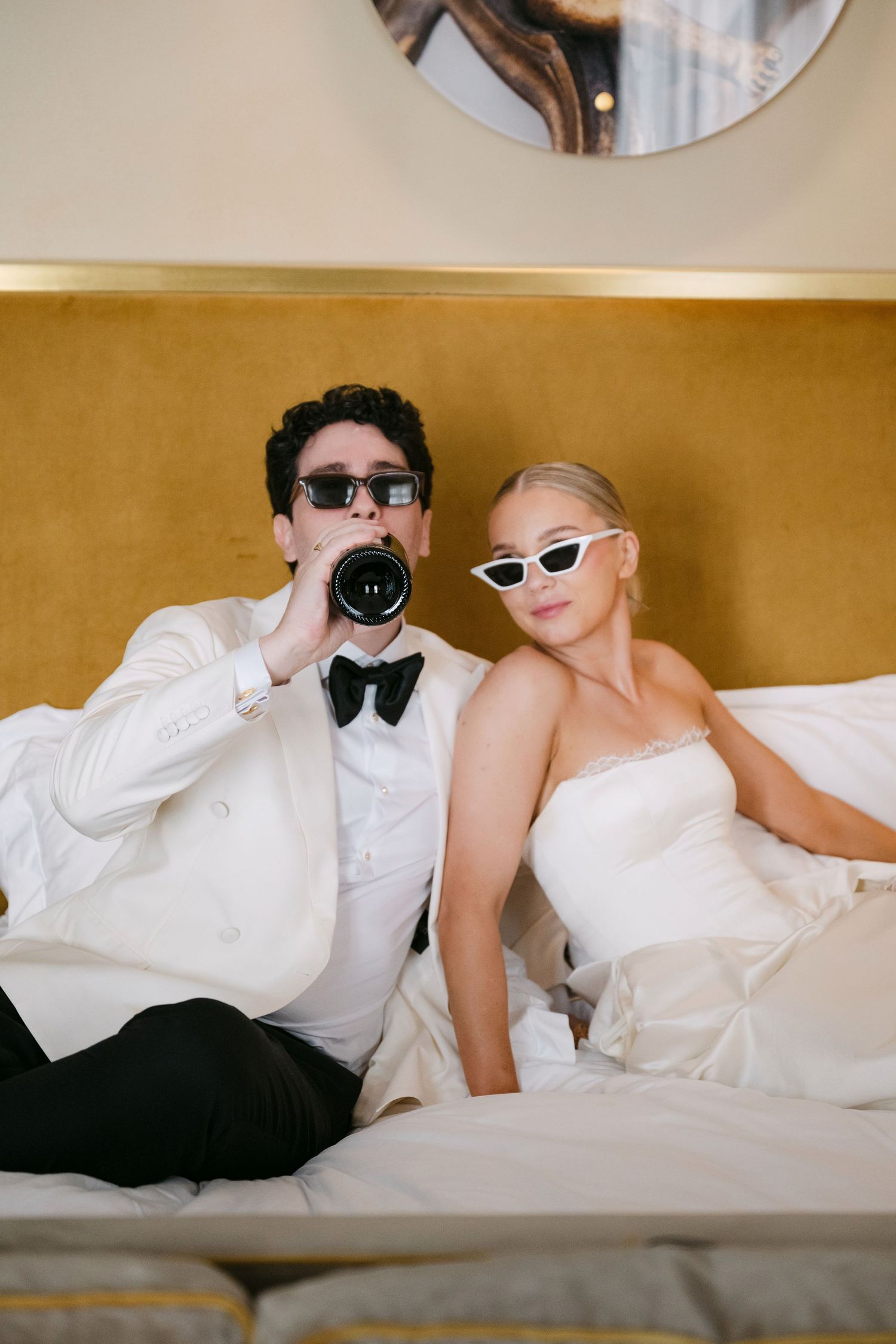 Artistic black and white photo series showing two people in white clothing lounging on a bed in moody lighting.