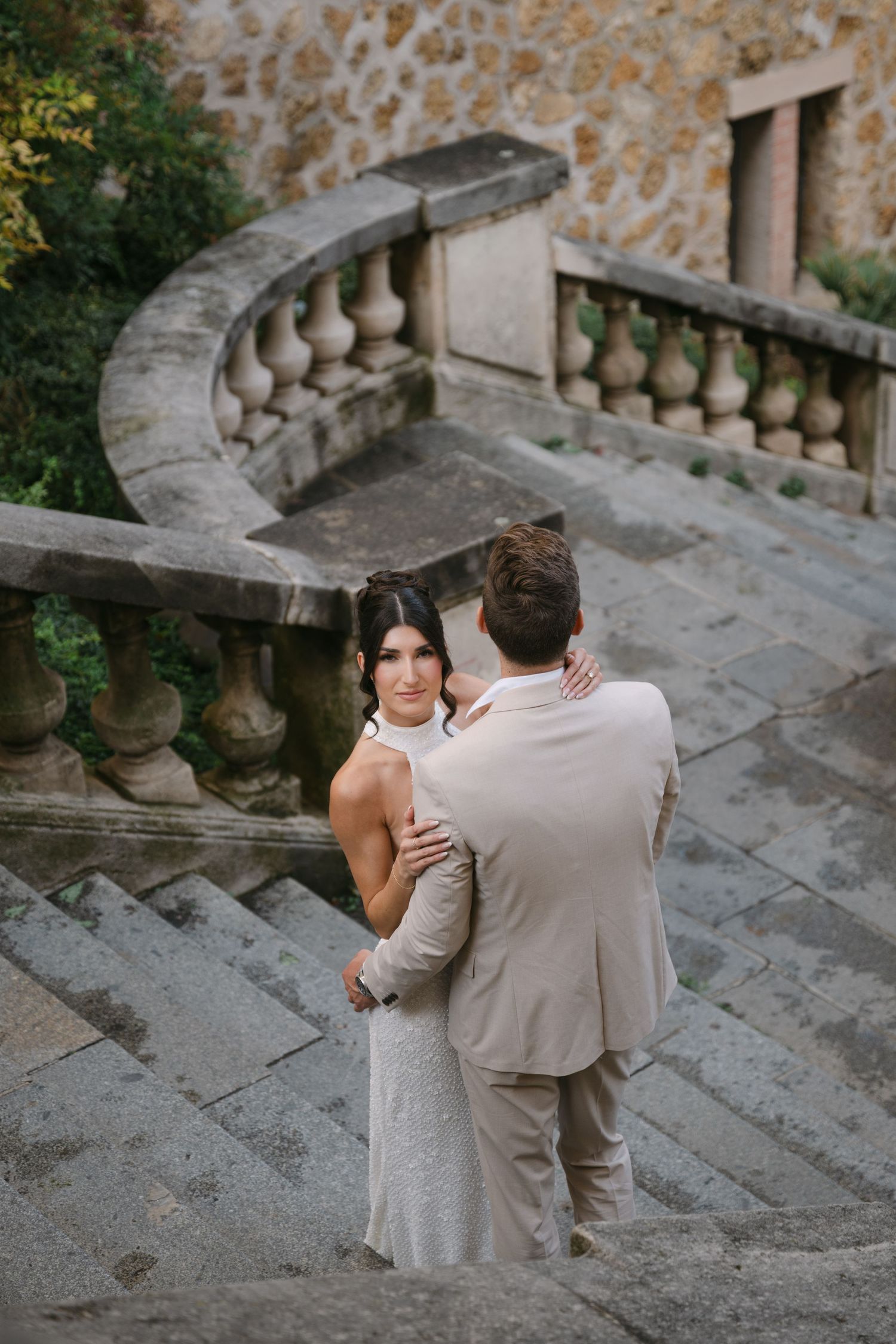 A couple embraces on historic stone steps with ornate balustrades.