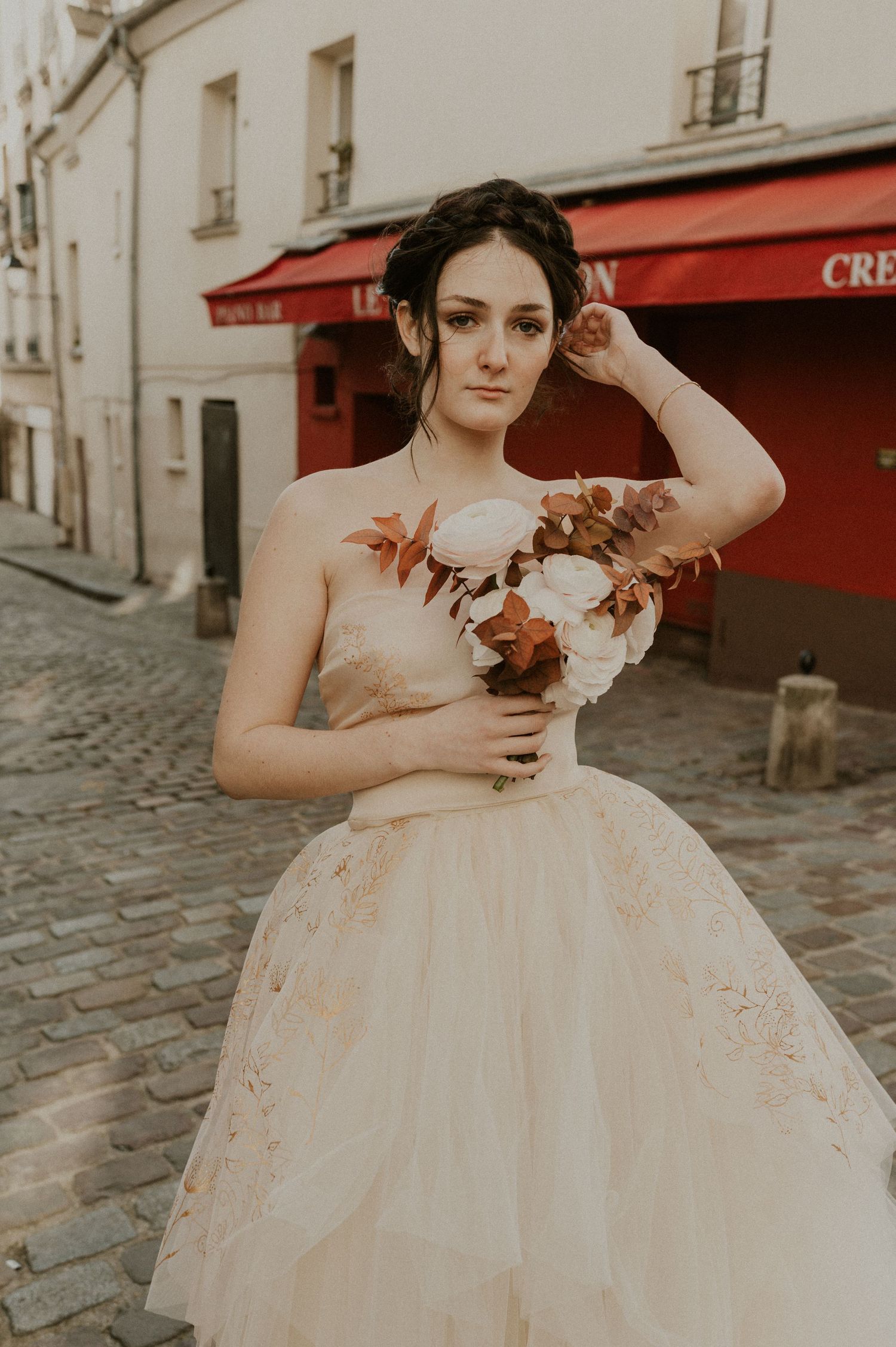 A romantic bridal portrait on cobblestone streets featuring a strapless ball gown and autumn bouquet.