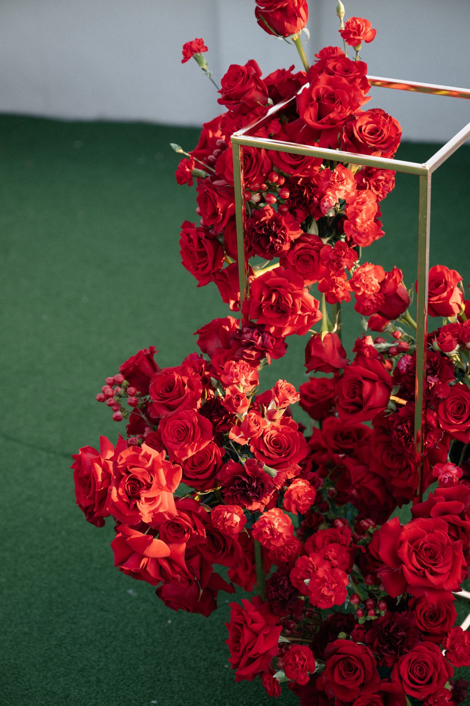 Vibrant red roses and floral arrangements create an elegant display against a green backdrop.