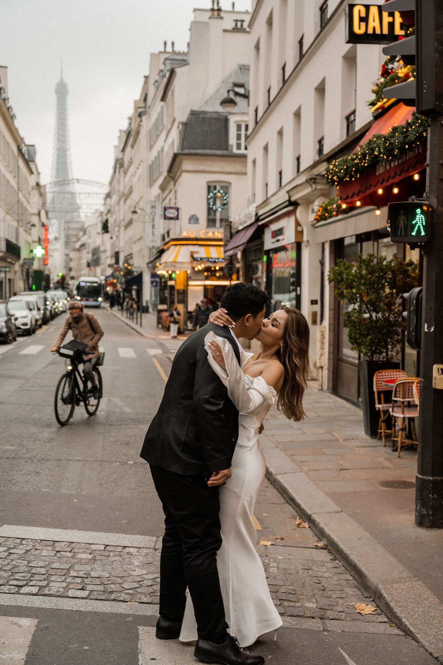 A romantic kiss on a Parisian street with the Eiffel Tower visible in the misty background.