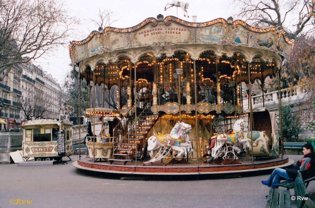 Vintage carousel with ornate decoration and lights in a Parisian square.