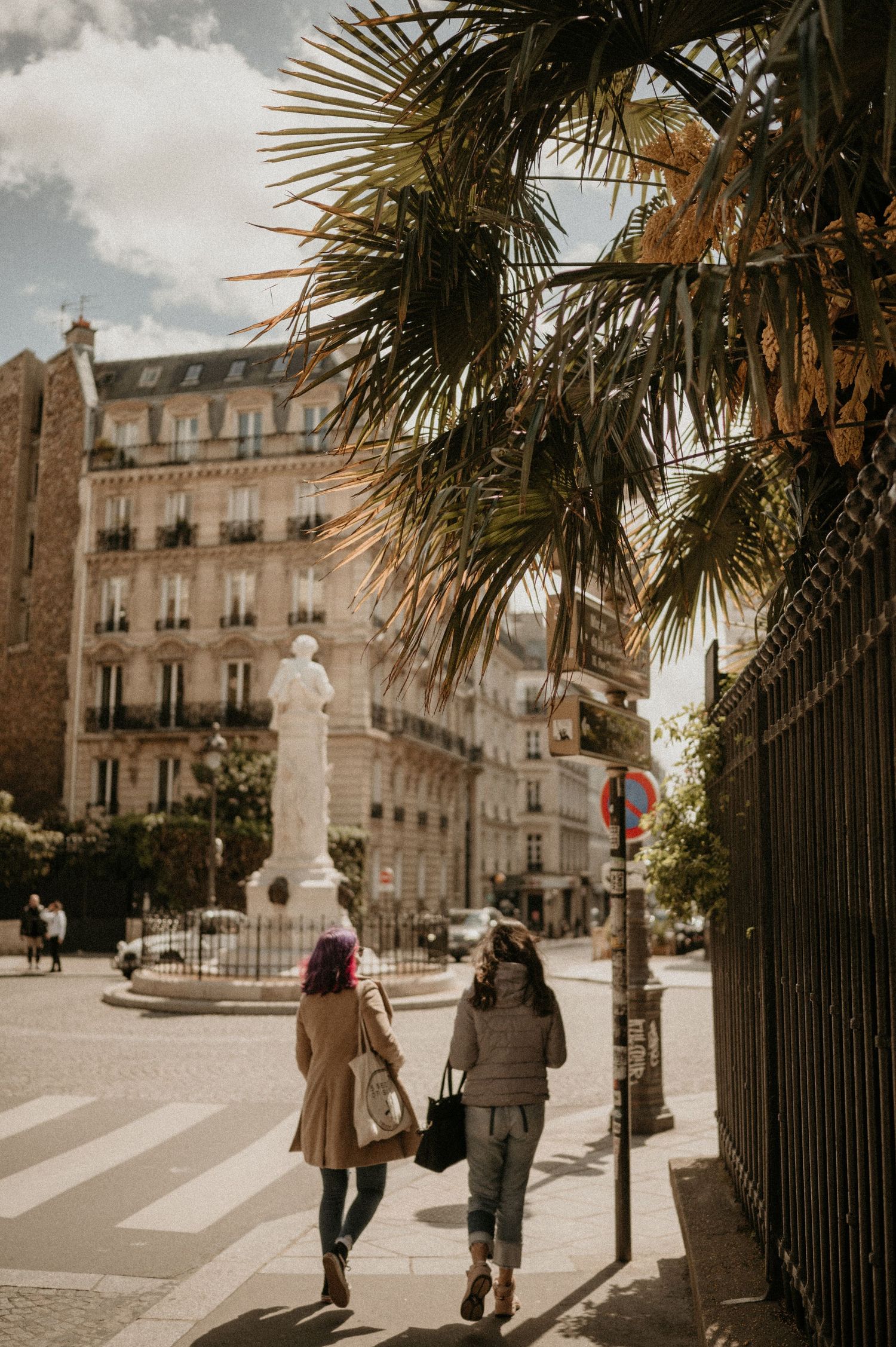 Atmospheric street scene in Paris with palm trees and classic architecture.