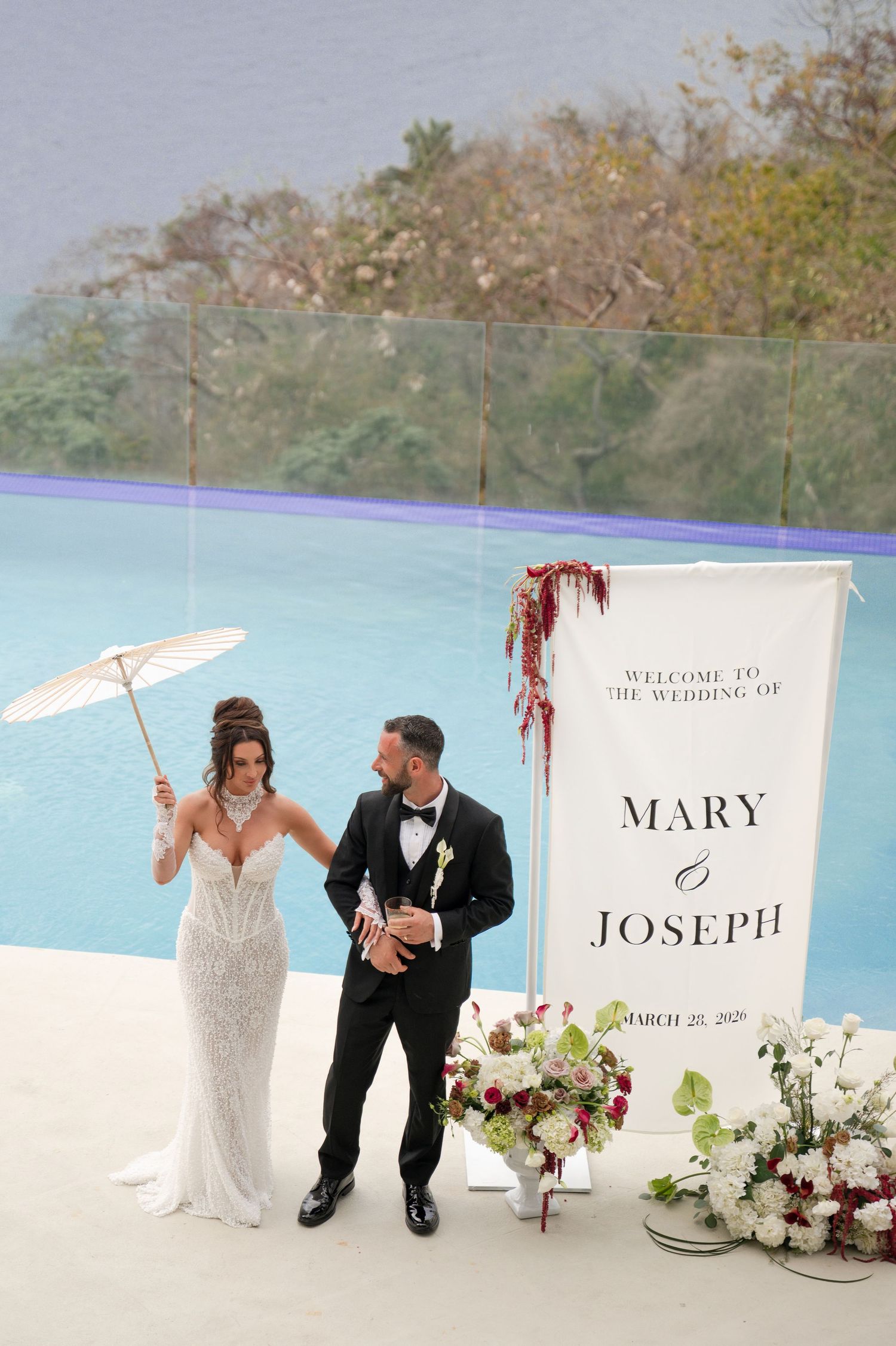 Bride and groom pose by wedding sign for Mary and Joseph on March 25, 2020, at an oceanview venue.