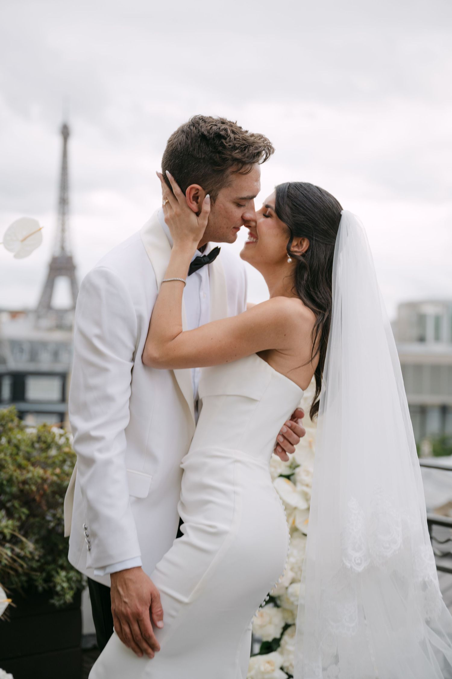 Bride and groom share a romantic kiss on a rooftop with the Eiffel Tower in the background in Paris.
