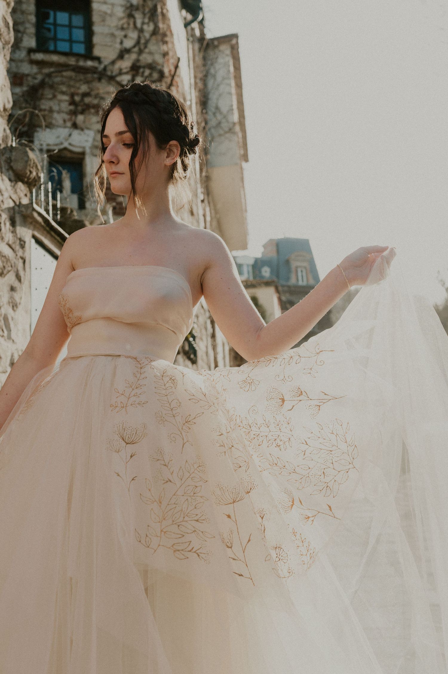 Close-up detail of delicate lace and tulle wedding gown in warm sunlight.