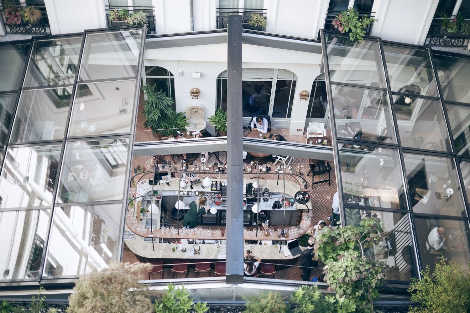 Aerial view of a modern glass-enclosed circular restaurant with indoor plants.