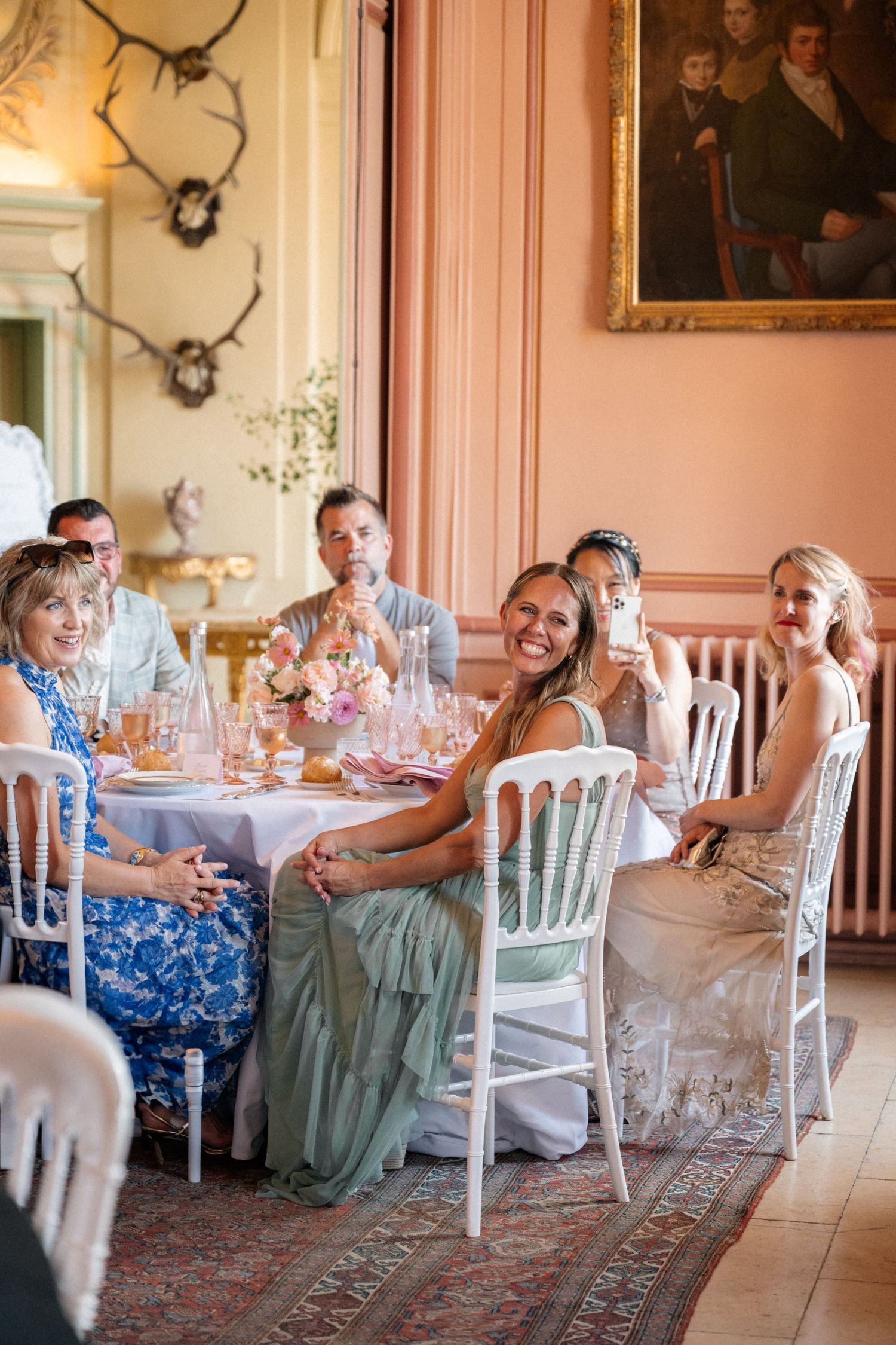 Wedding guests seated at a decorated table in an elegant French chateau dining room.