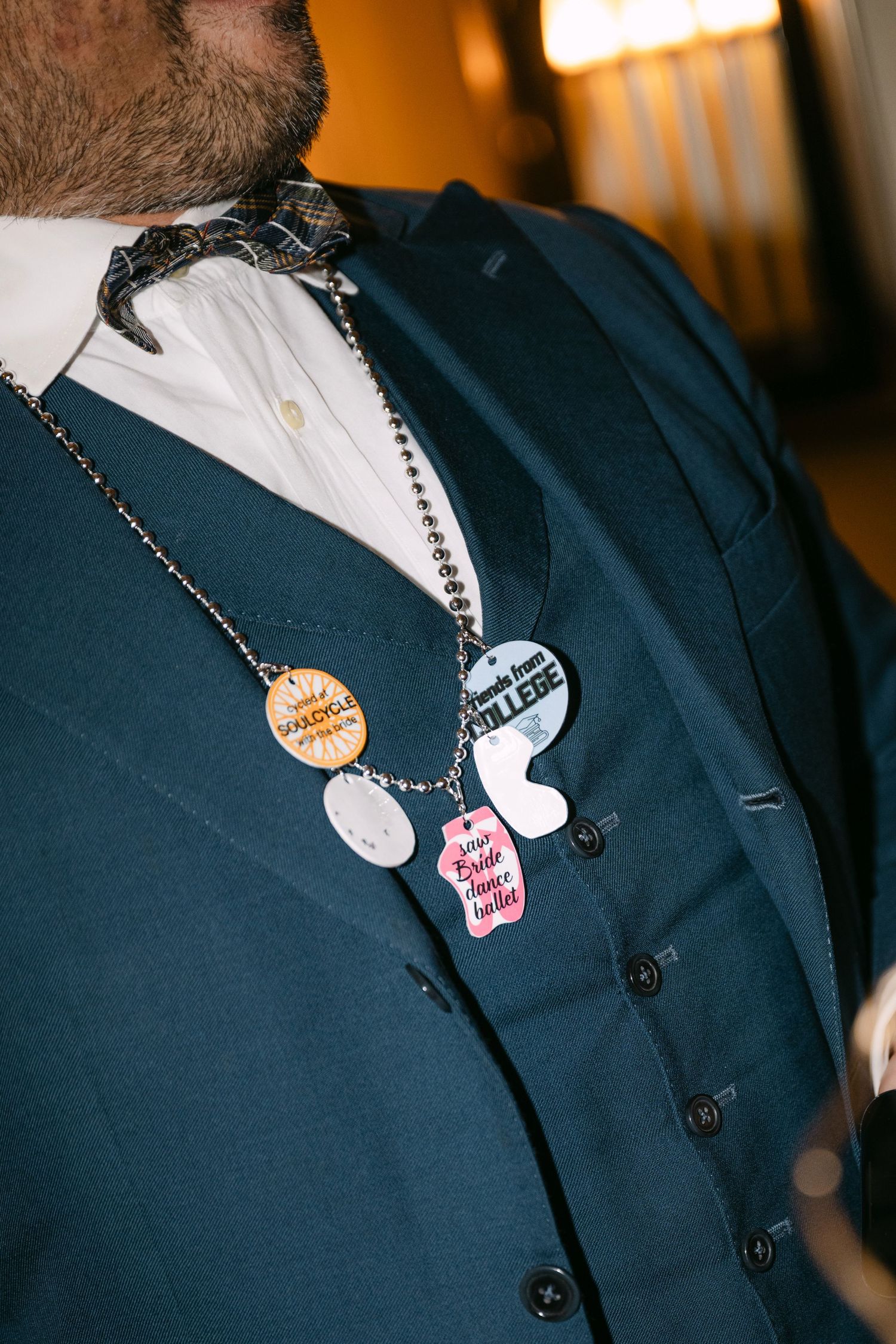 Close-up of decorative medallion necklaces on a navy blue suit jacket at a formal event.