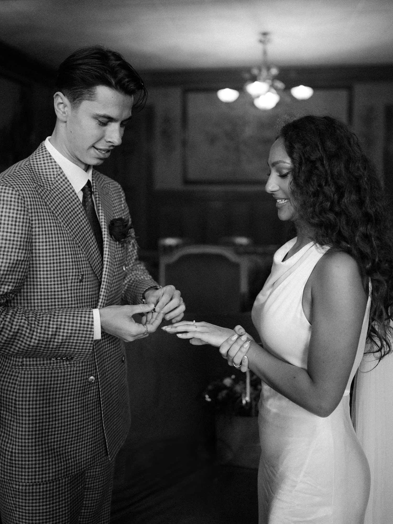 A couple exchanges wedding rings in a classic black and white ceremony photo.