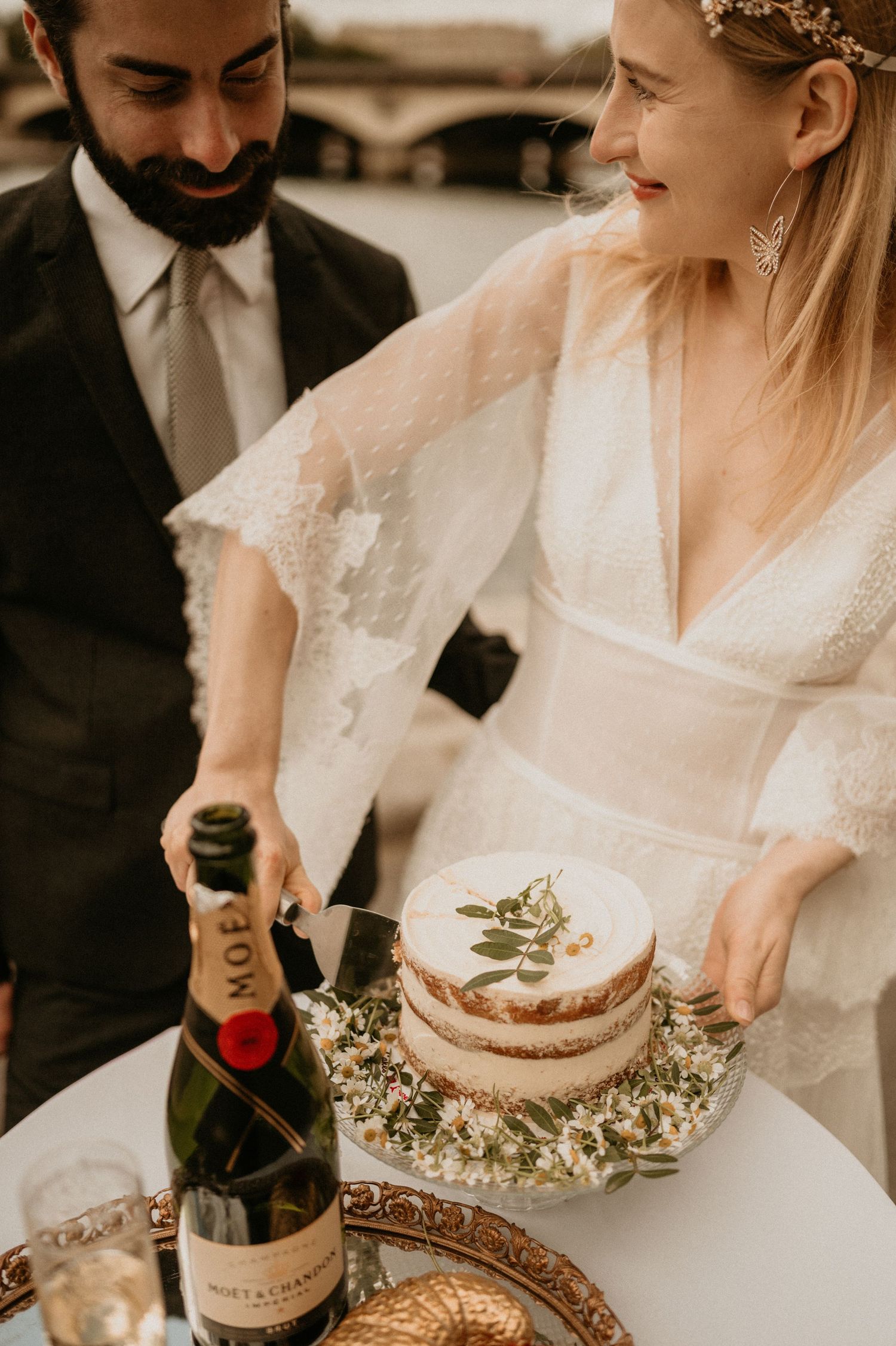 Newlyweds cutting their wedding cake with champagne during a Paris celebration.