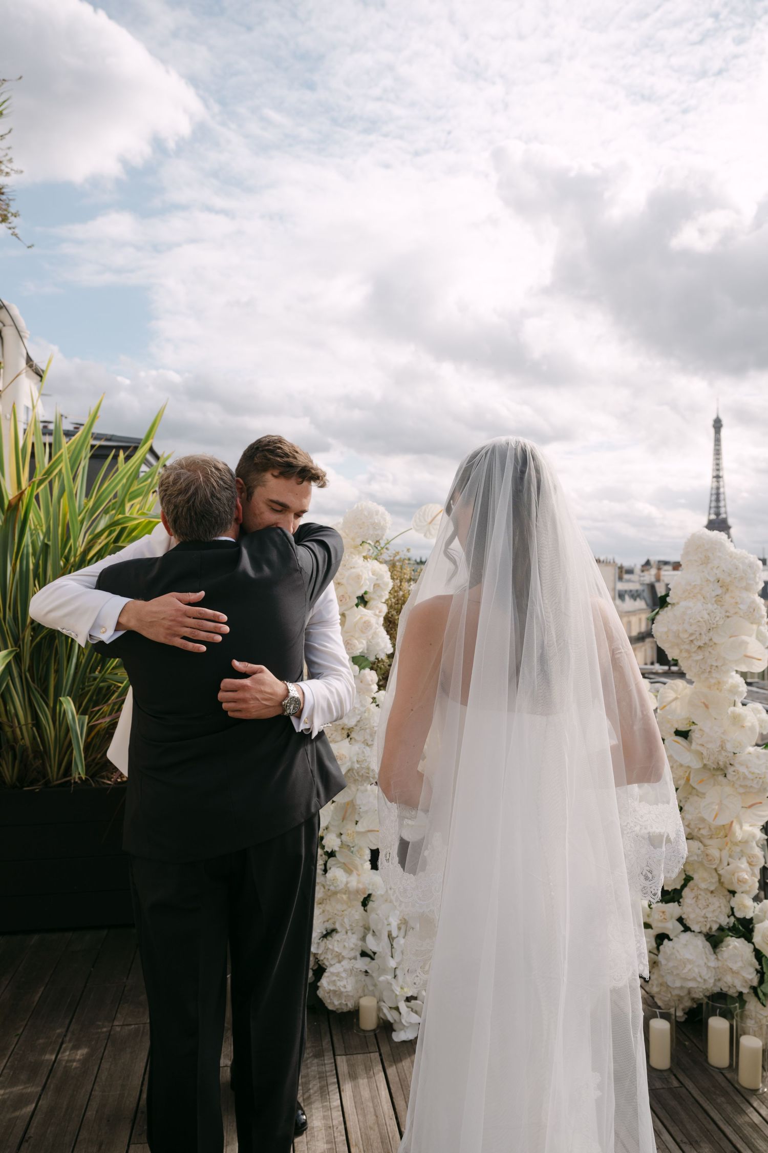 Emotional first look sequence between wedding couple with white floral decorations and cloudy sky backdrop.