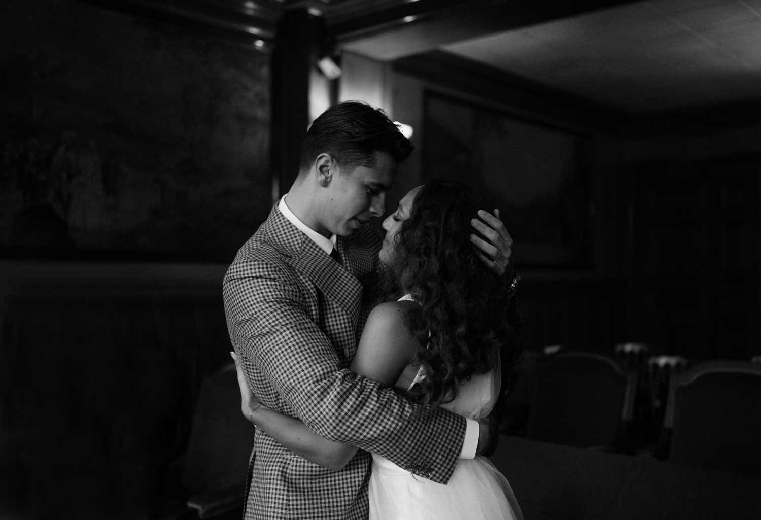 A romantic black and white photo of a couple embracing in an elegantly decorated room.