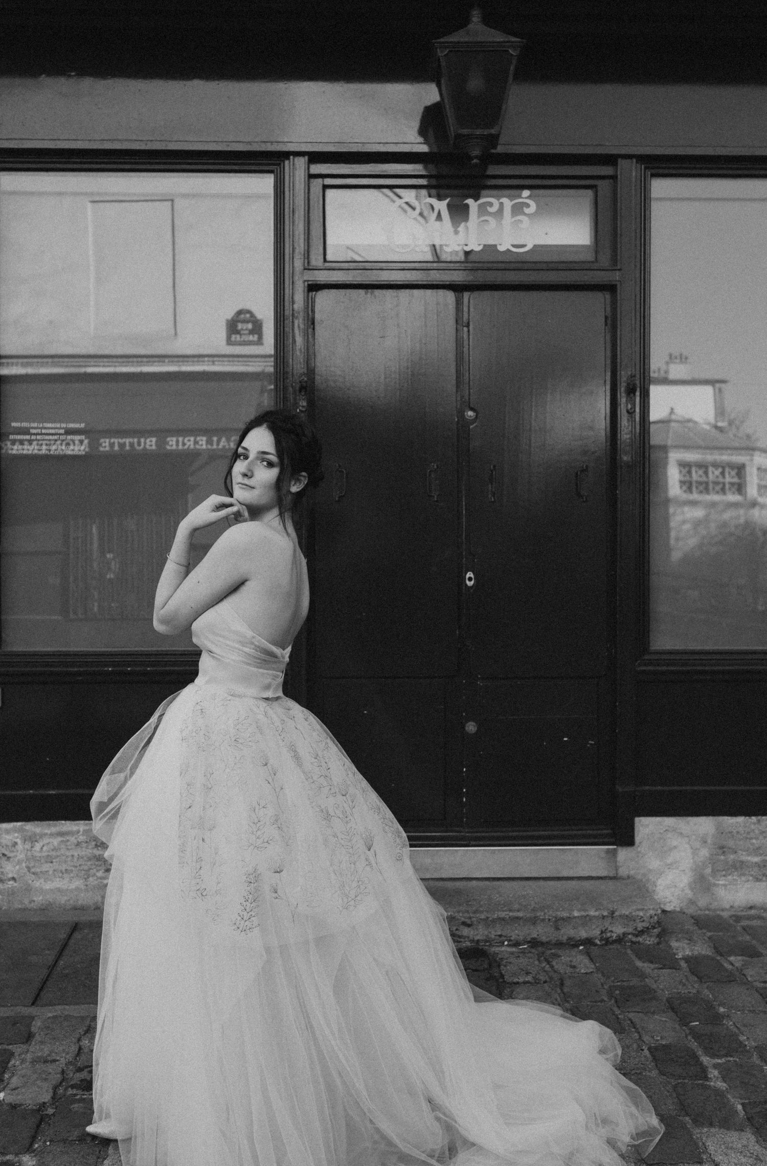 Dramatic black and white bridal portrait featuring strapless gown against urban storefront.