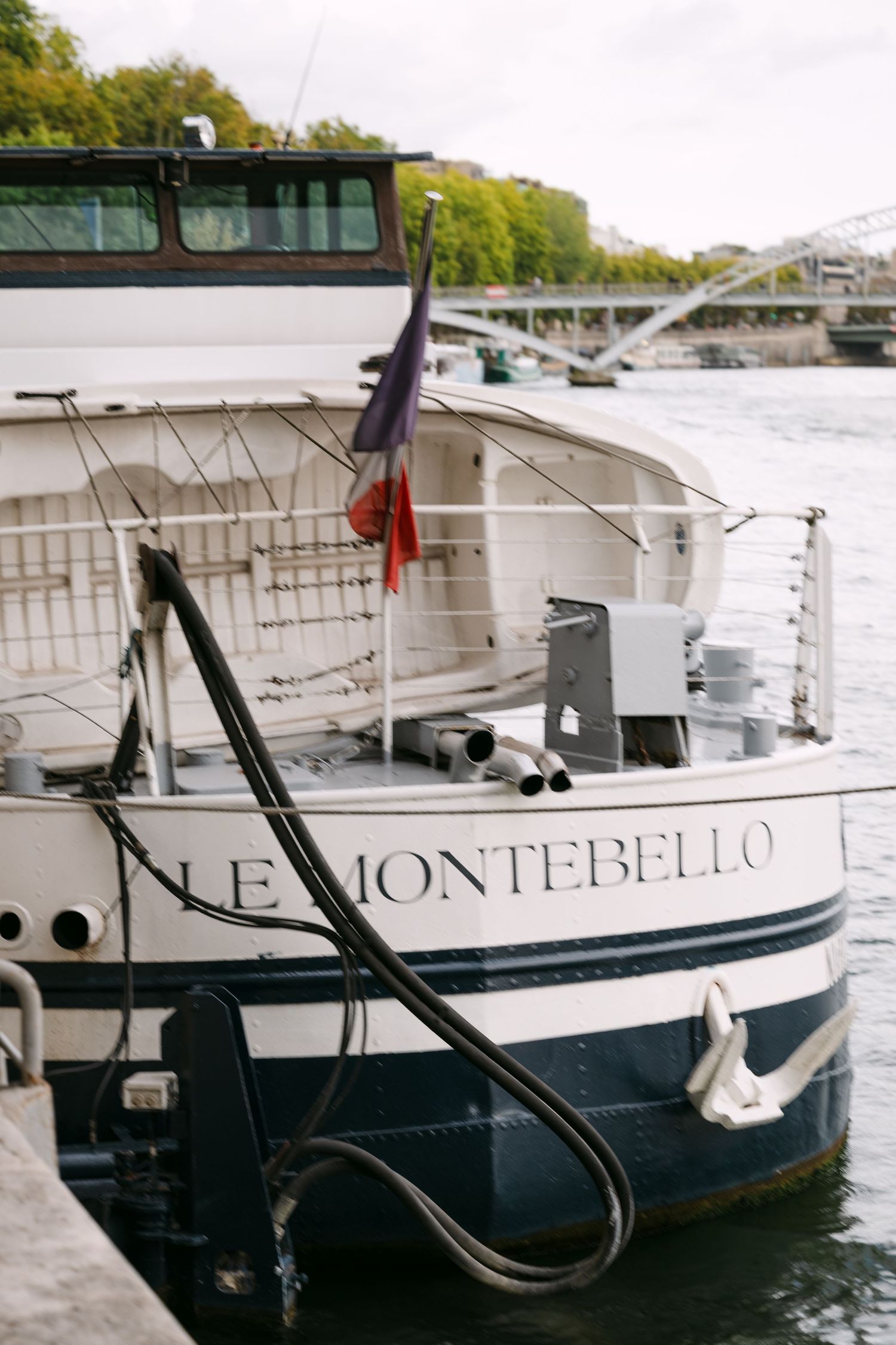 Le Montebello boat docked along the Seine River in Paris with a French flag flying at the stern.