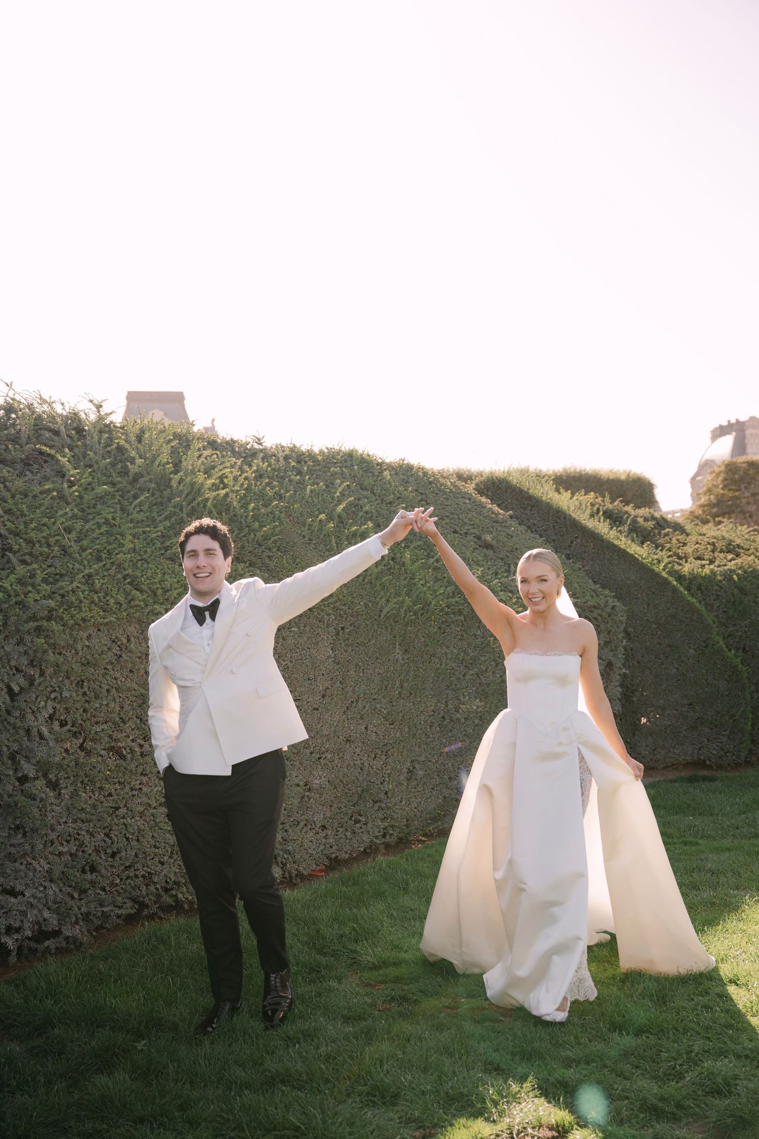 Joyful newlyweds holding hands and celebrating in a lush garden after their wedding ceremony.