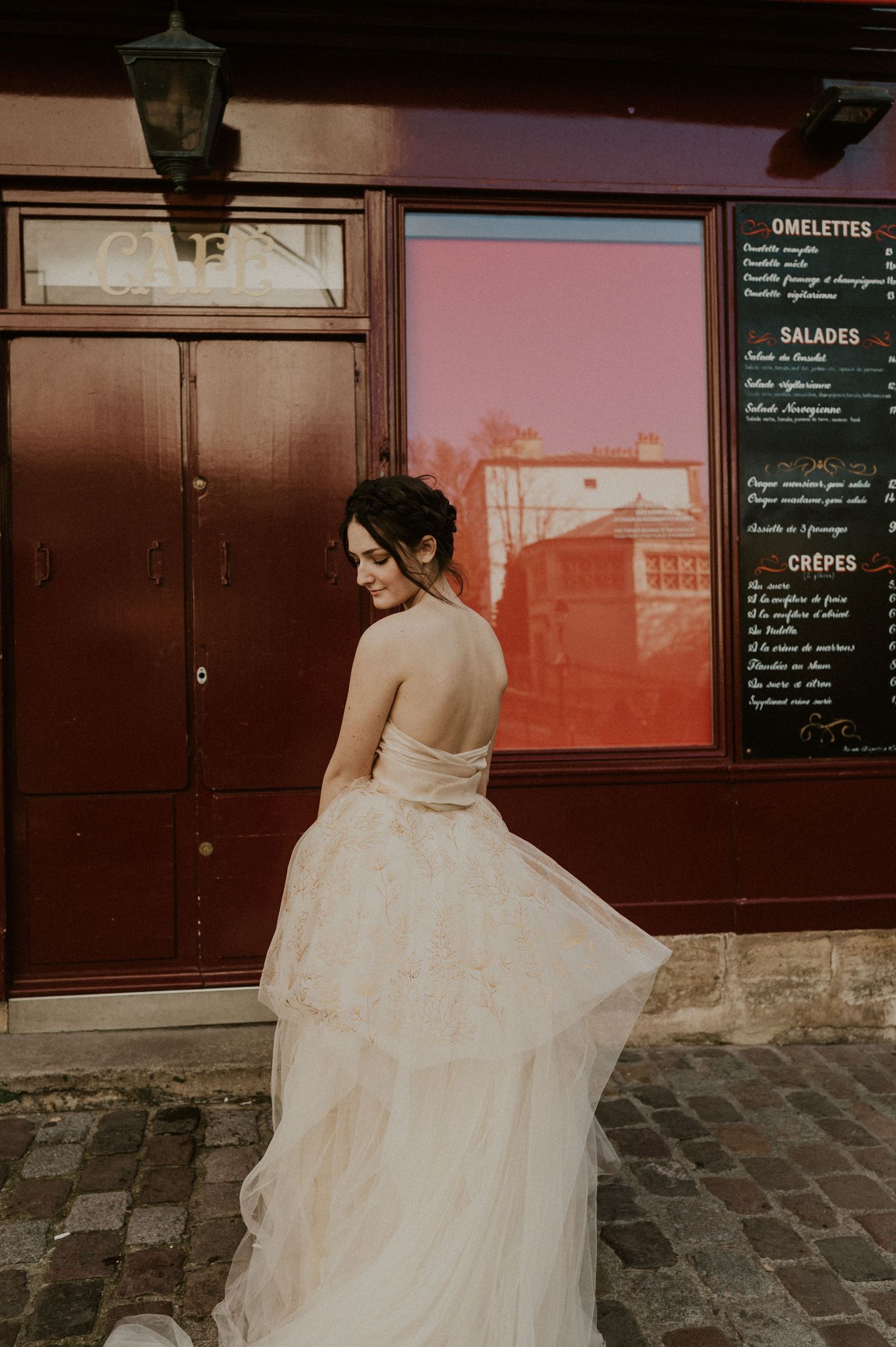 Dreamy wedding photograph featuring flowing dress against burgundy restaurant exterior with menu board.