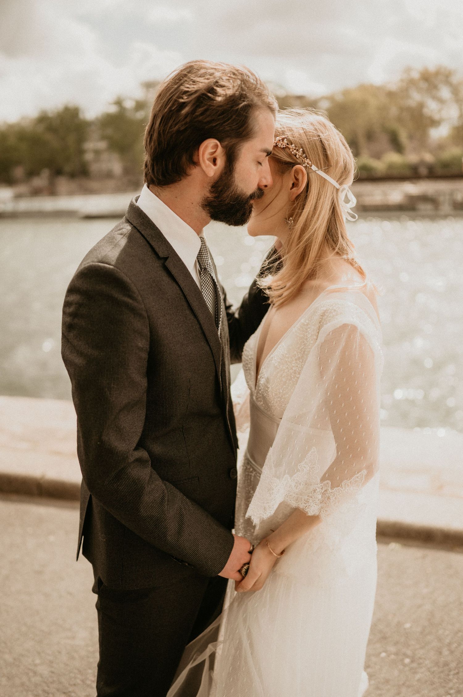 Candid wedding photo capturing intimate moment between newlyweds by waterfront.