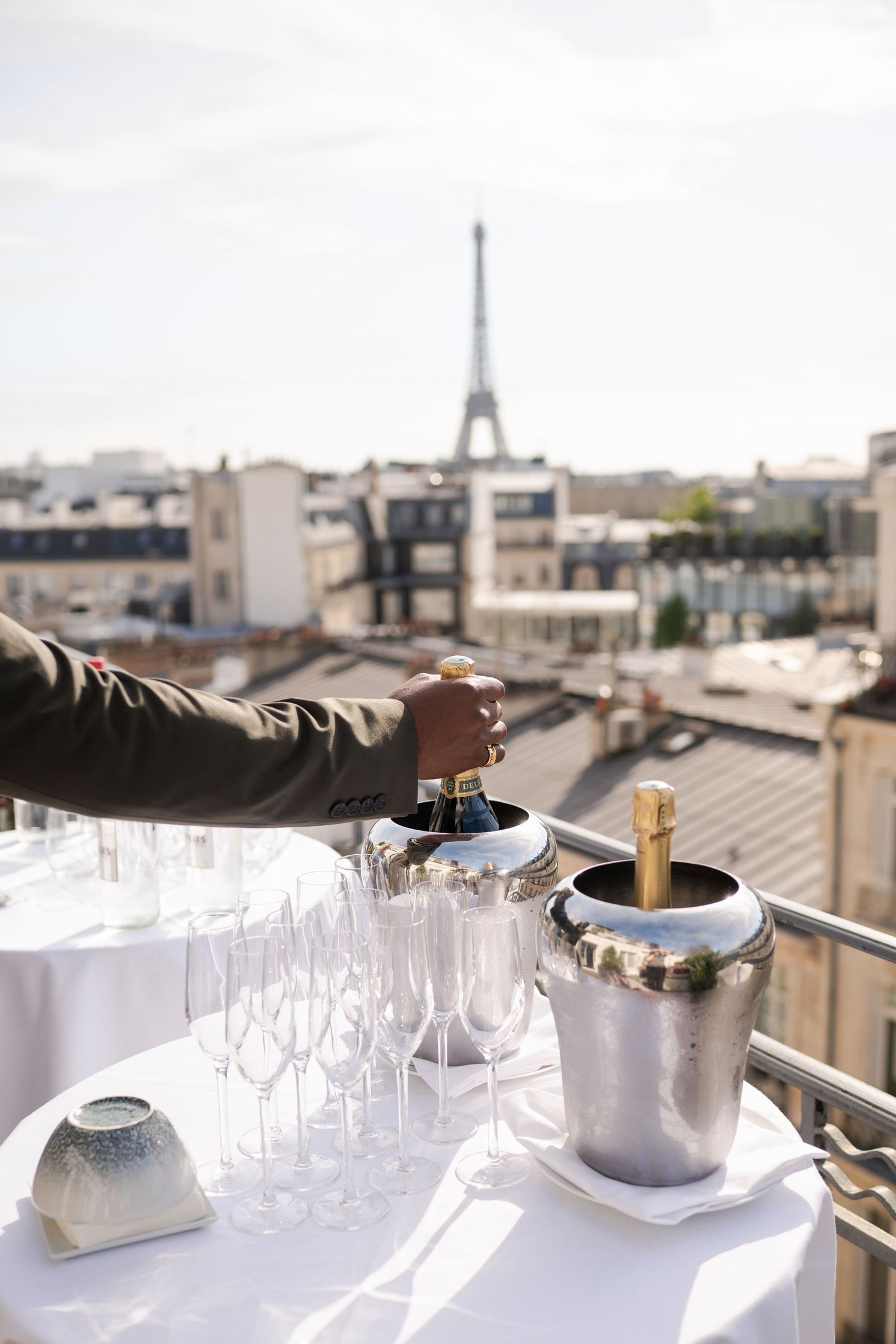 Champagne glasses and bottles on a rooftop terrace with the Eiffel Tower in the background in Paris, France.