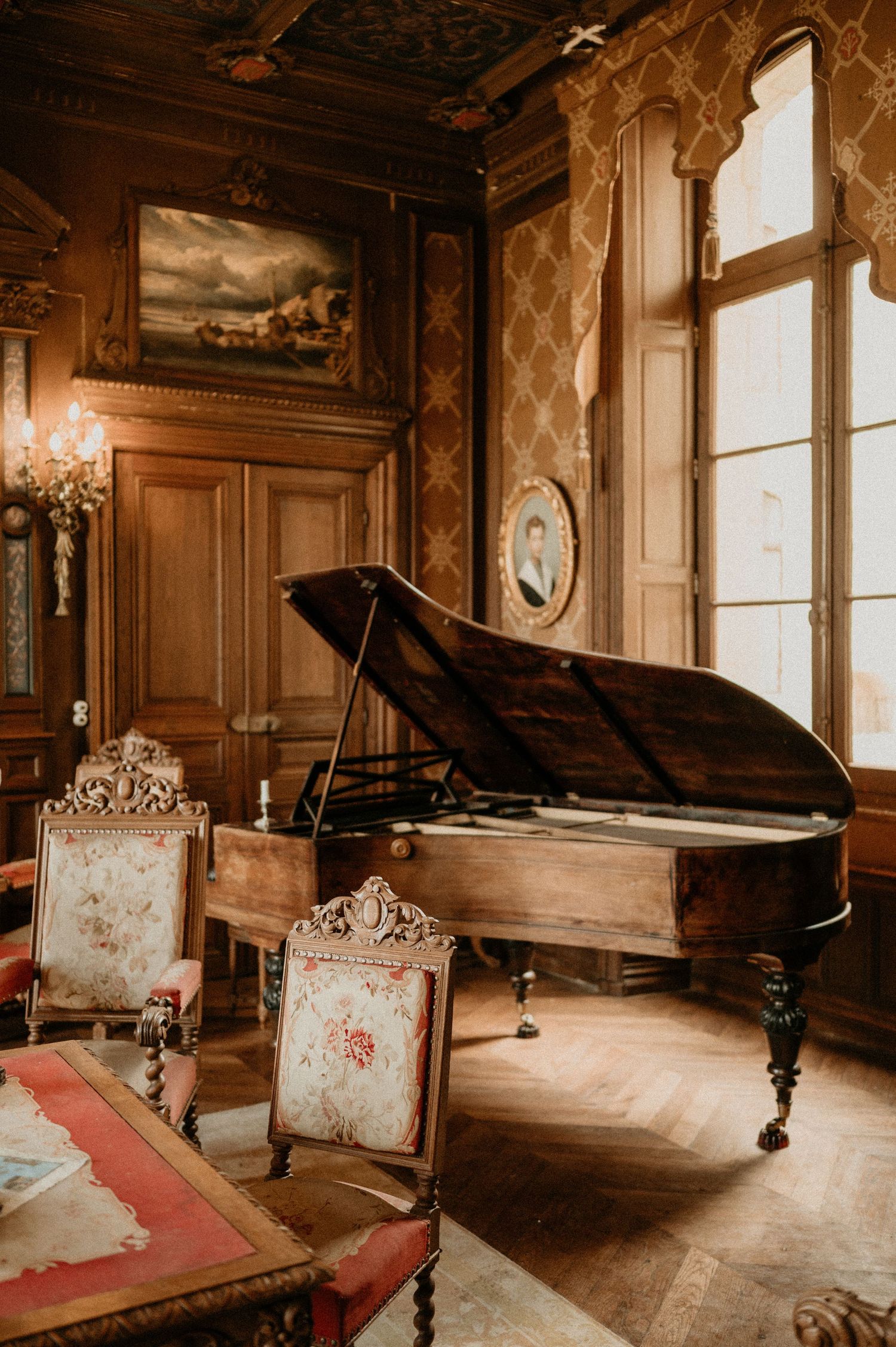 Opulent vintage room with grand piano and ornate chairs in classic French style.