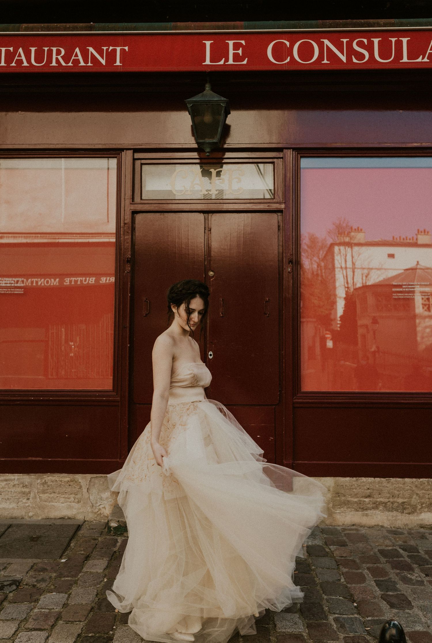 Elegant bridal portrait outside Le Consulat restaurant with flowing tulle gown.