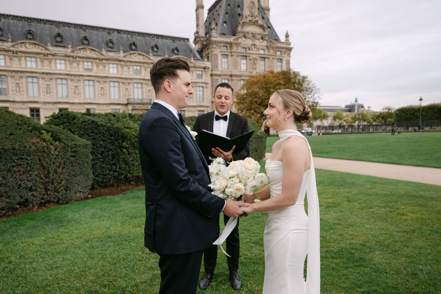 A couple shares a joyful moment together on a grand lawn with an elegant European palace in the background.