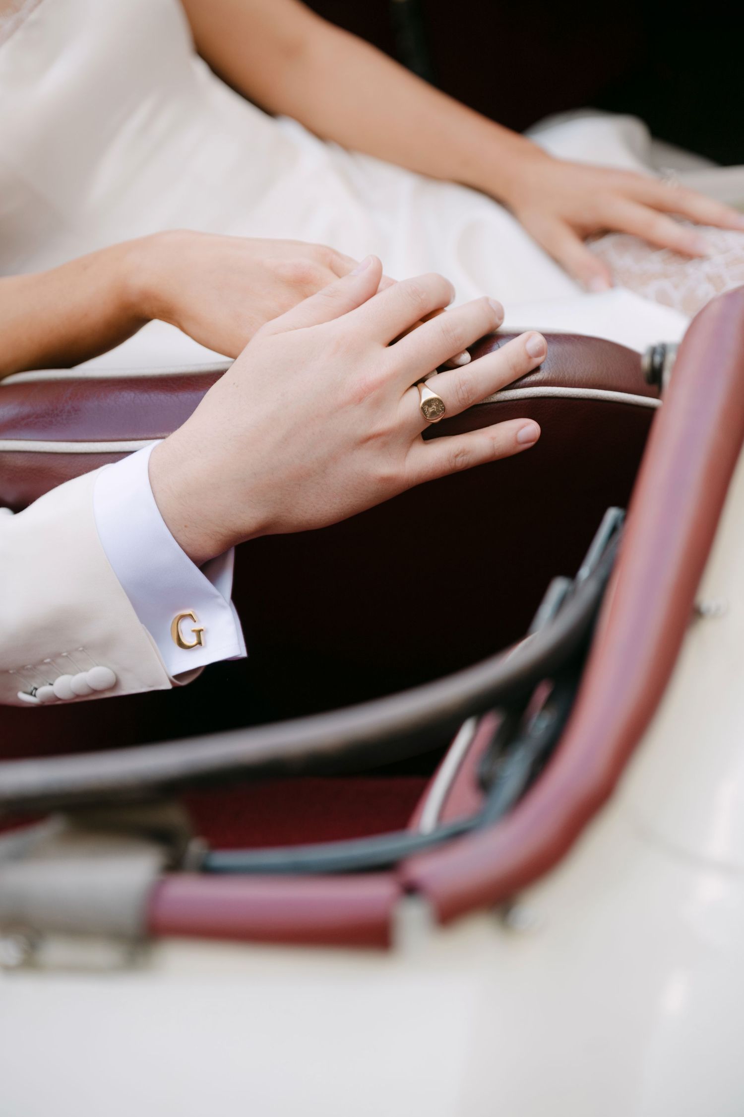 Close-up view of hands resting on a leather armrest showing delicate finger movements and elegant positioning.